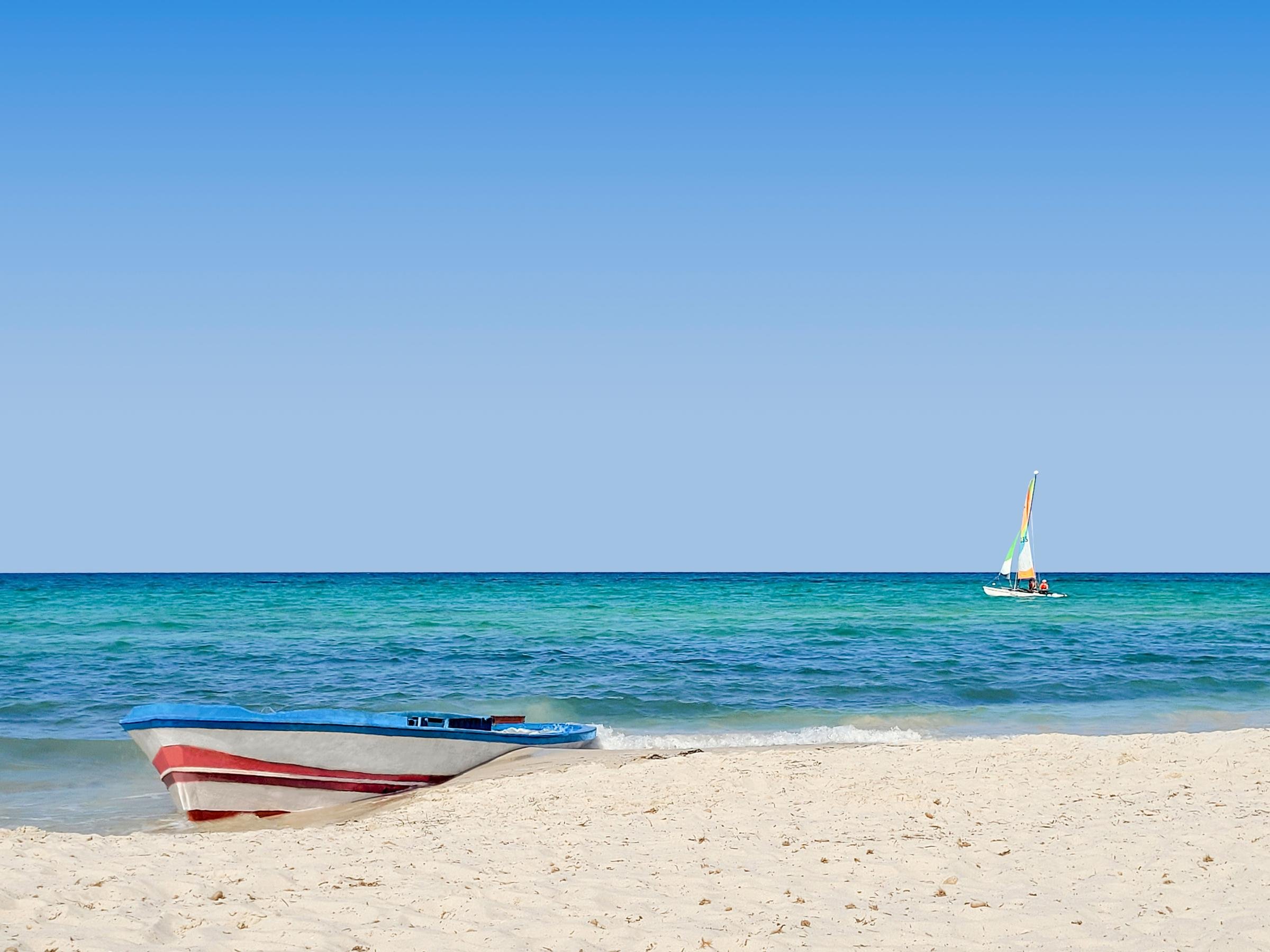 Blick auf einen weißen Strand mit Booten und klarem blauen Himmel bei Aldiana Premium Cluburlaub