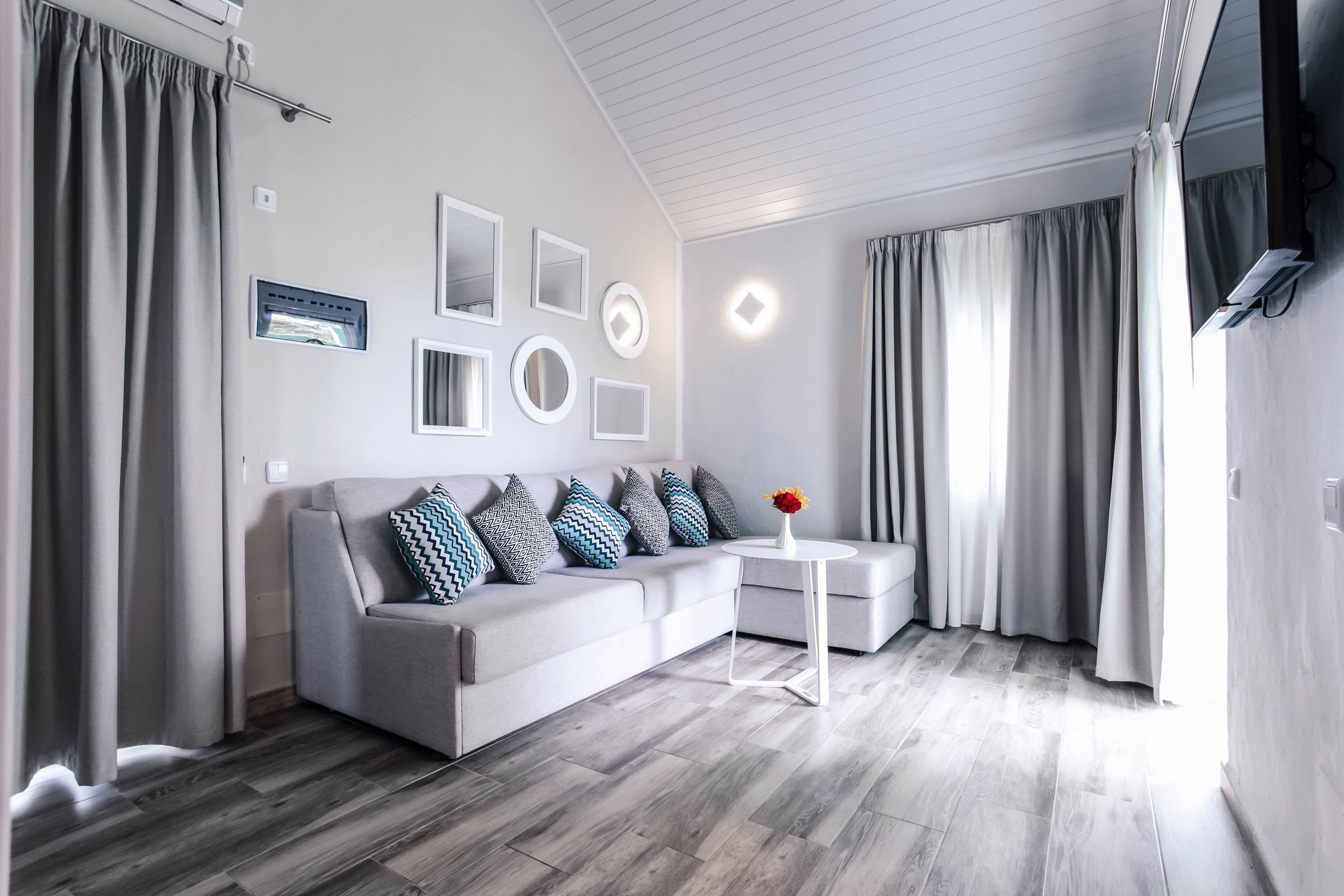 Ein schönes Hotelzimmer mit Sofa, Bildern und Fenster mit Vorhängen unter dem Dach