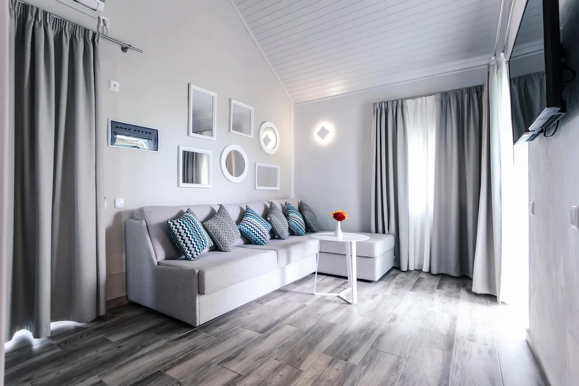 Ein schönes Hotelzimmer mit Sofa, Bildern und Fenster mit Vorhängen unter dem Dach