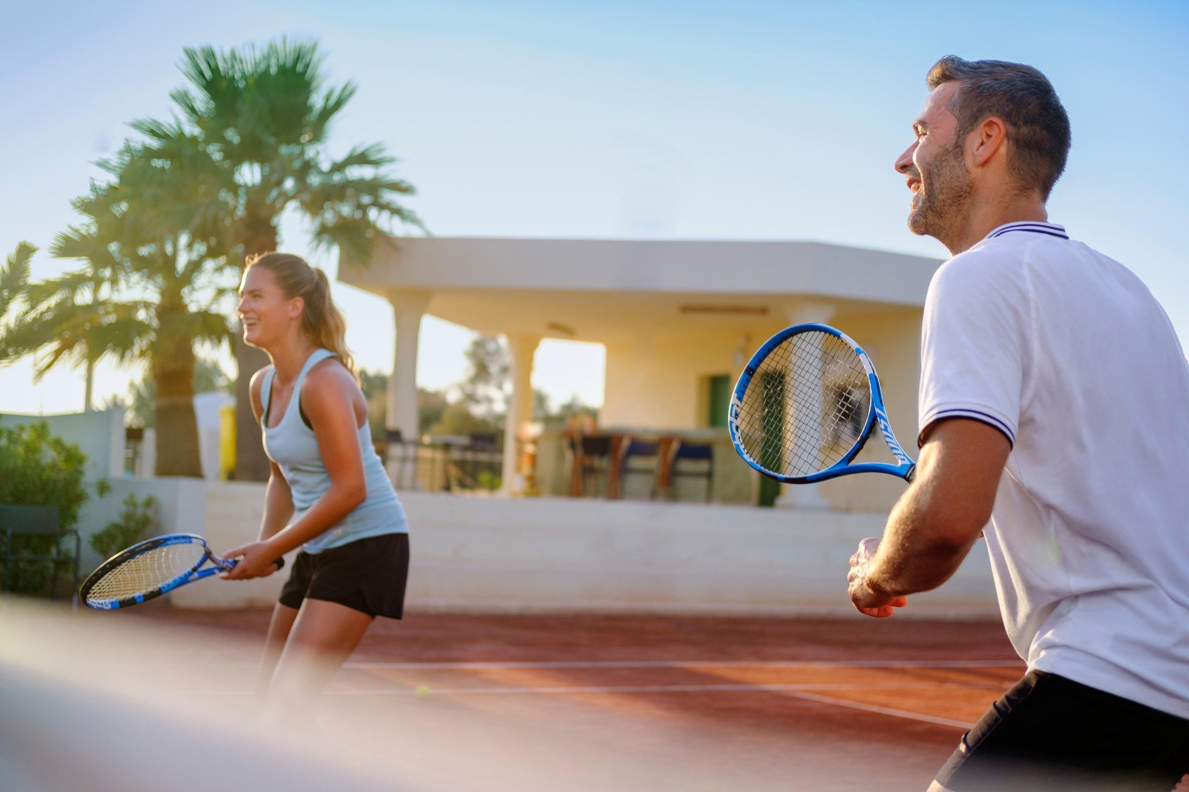 Zwei Personen beim Tennisspielen auf einer Sonnenterrasse im Premium Cluburlaub bei Aldiana