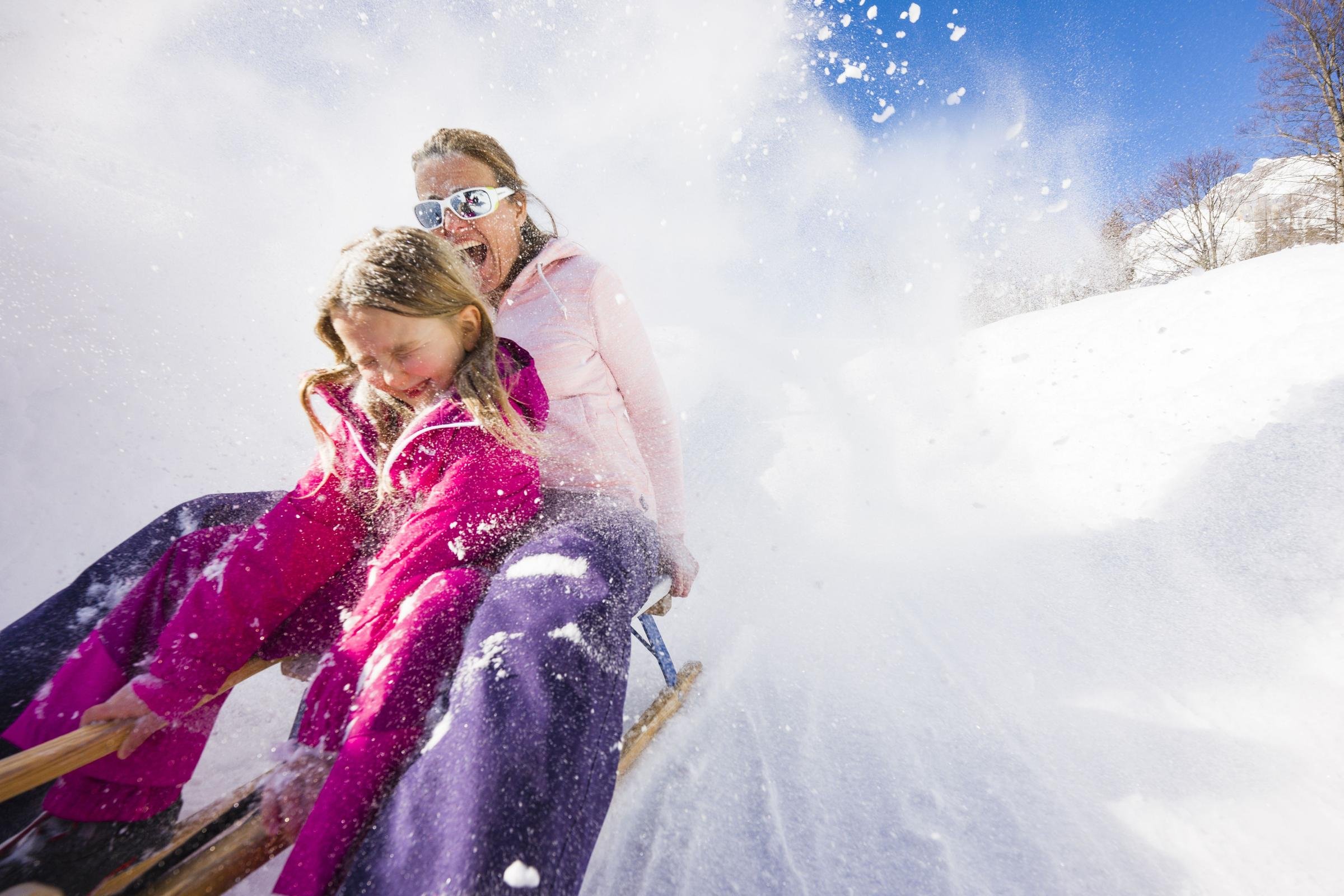 Familie beim Snowboardfahren im Schnee, Spaß im Winterurlaub bei Aldiana