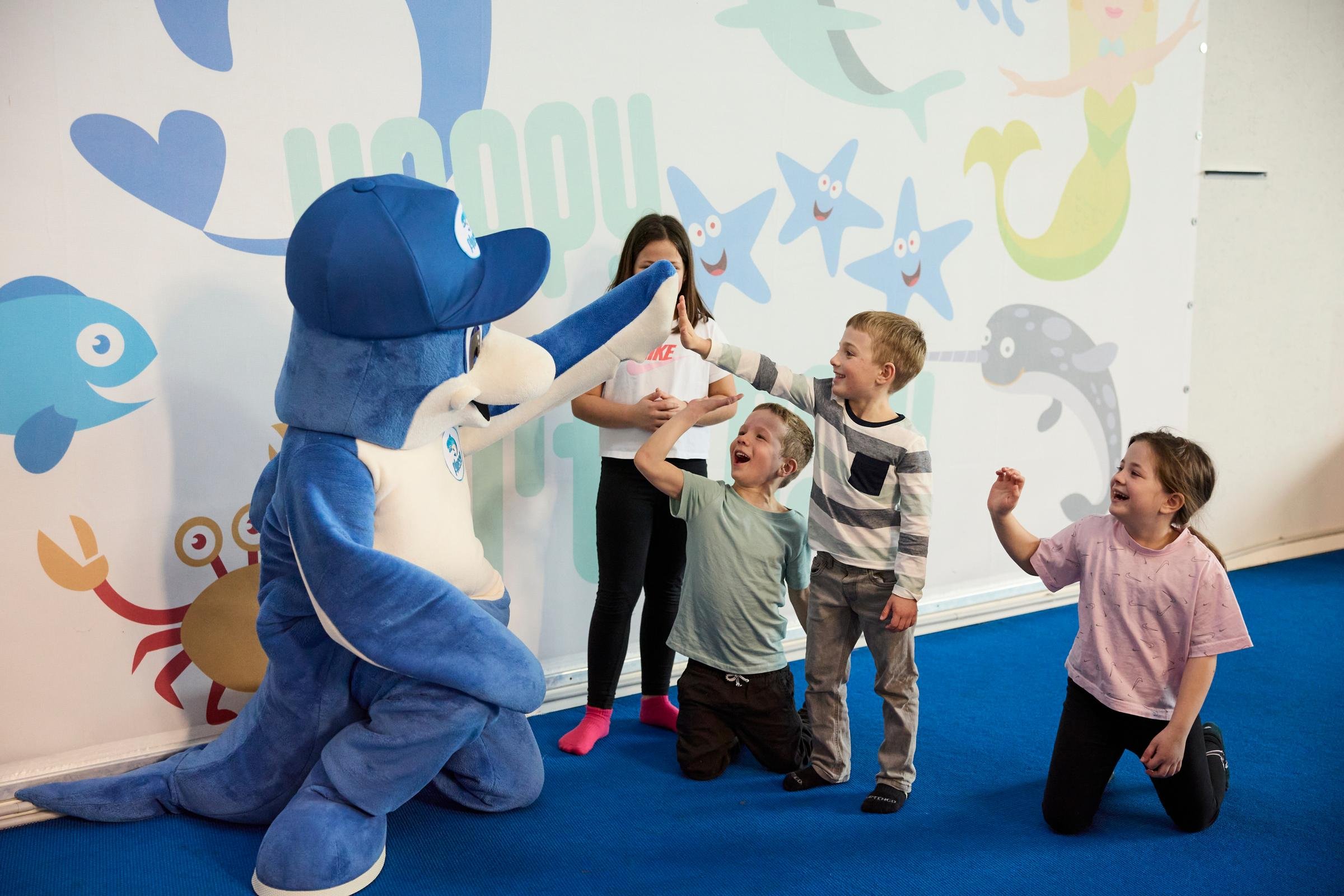 Kinder spielen mit dem Maskottchen bei einem Kinderprogramm im Premium Cluburlaub von Aldiana
