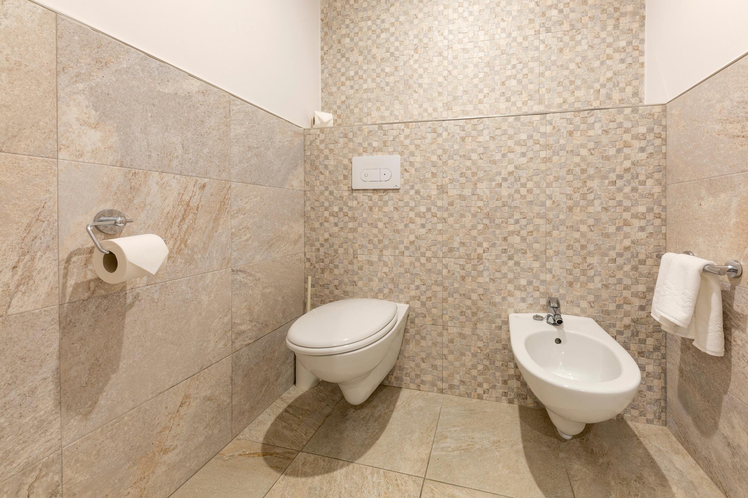 Gut ausgestattetes Badezimmer mit WC und Bidet, modernes Design, barrierefrei.