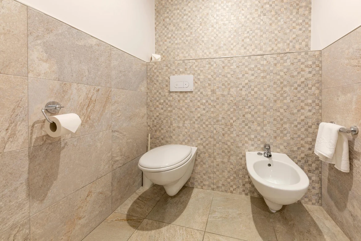 Gut ausgestattetes Badezimmer mit WC und Bidet, modernes Design, barrierefrei.