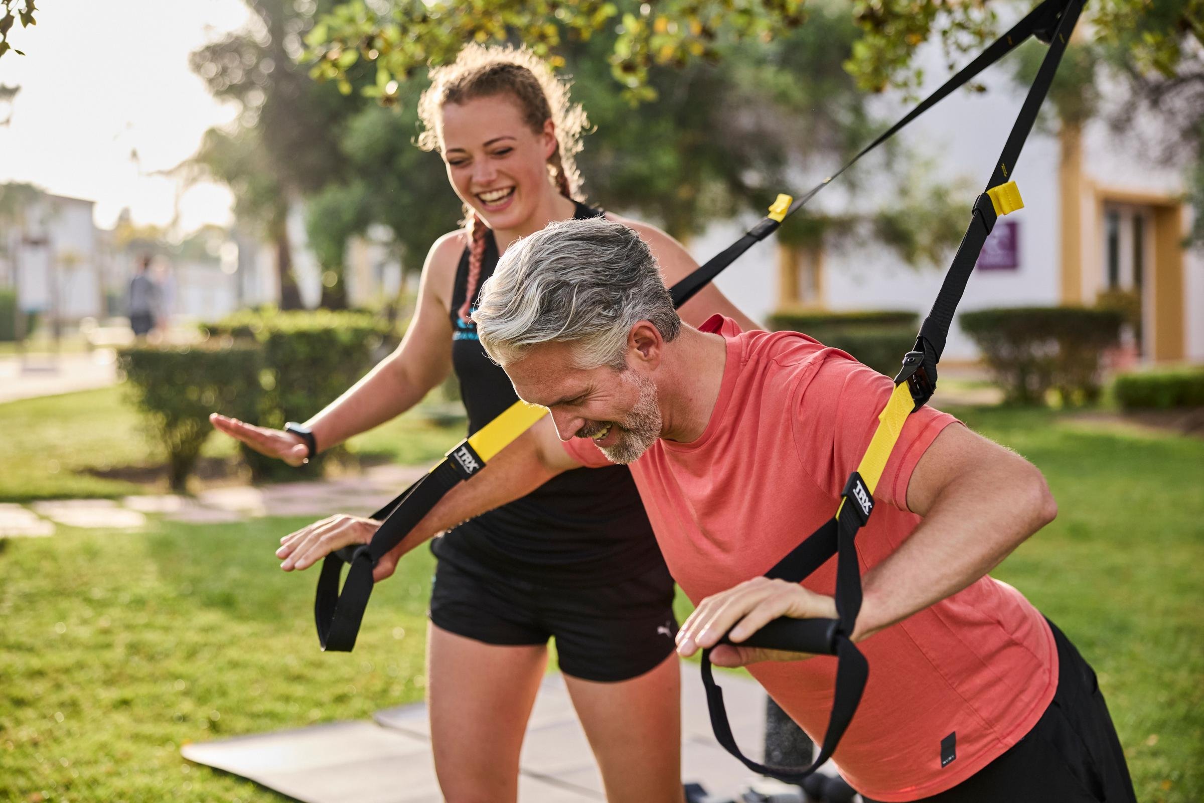 Frau trainiert mit Fitnessgürtel im sonnigen Park, Premium Cluburlaub bei Aldiana