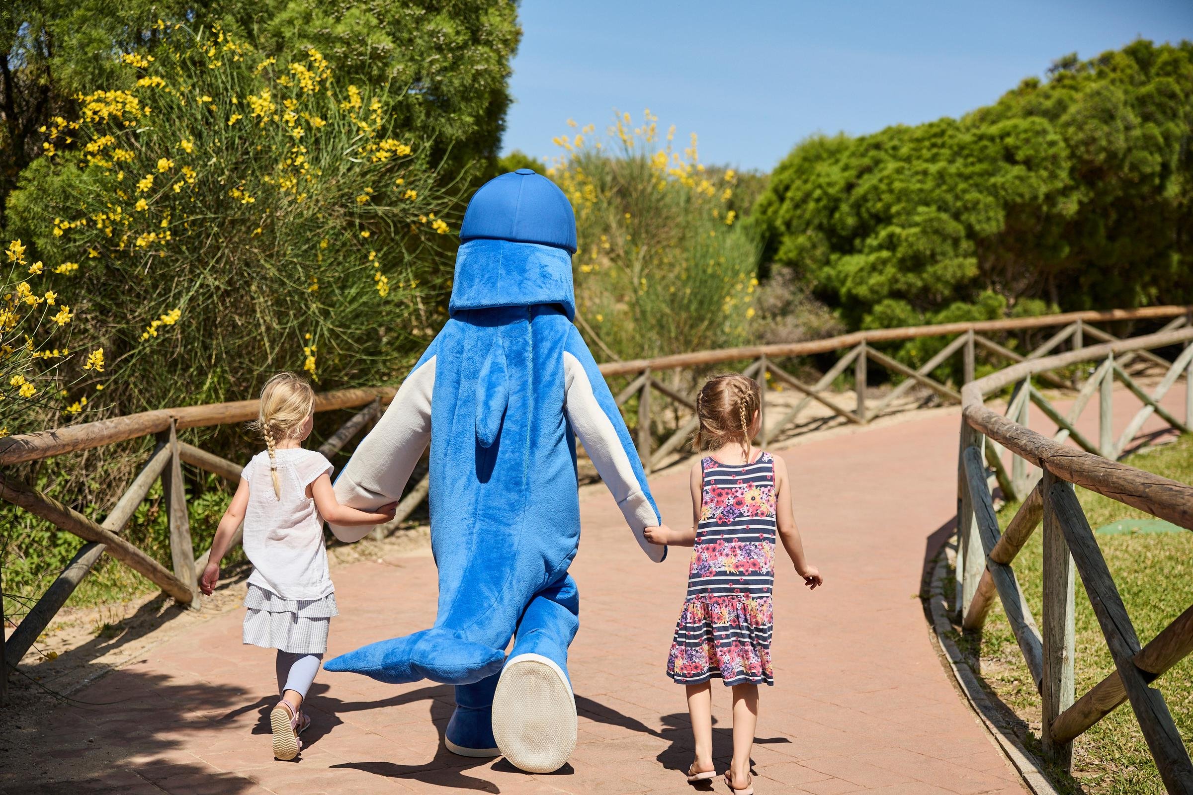 Familien beim kindgerechten Aldiana Cluburlaub im grünen Park, inklusive Maskottchen, Natur und Spaß