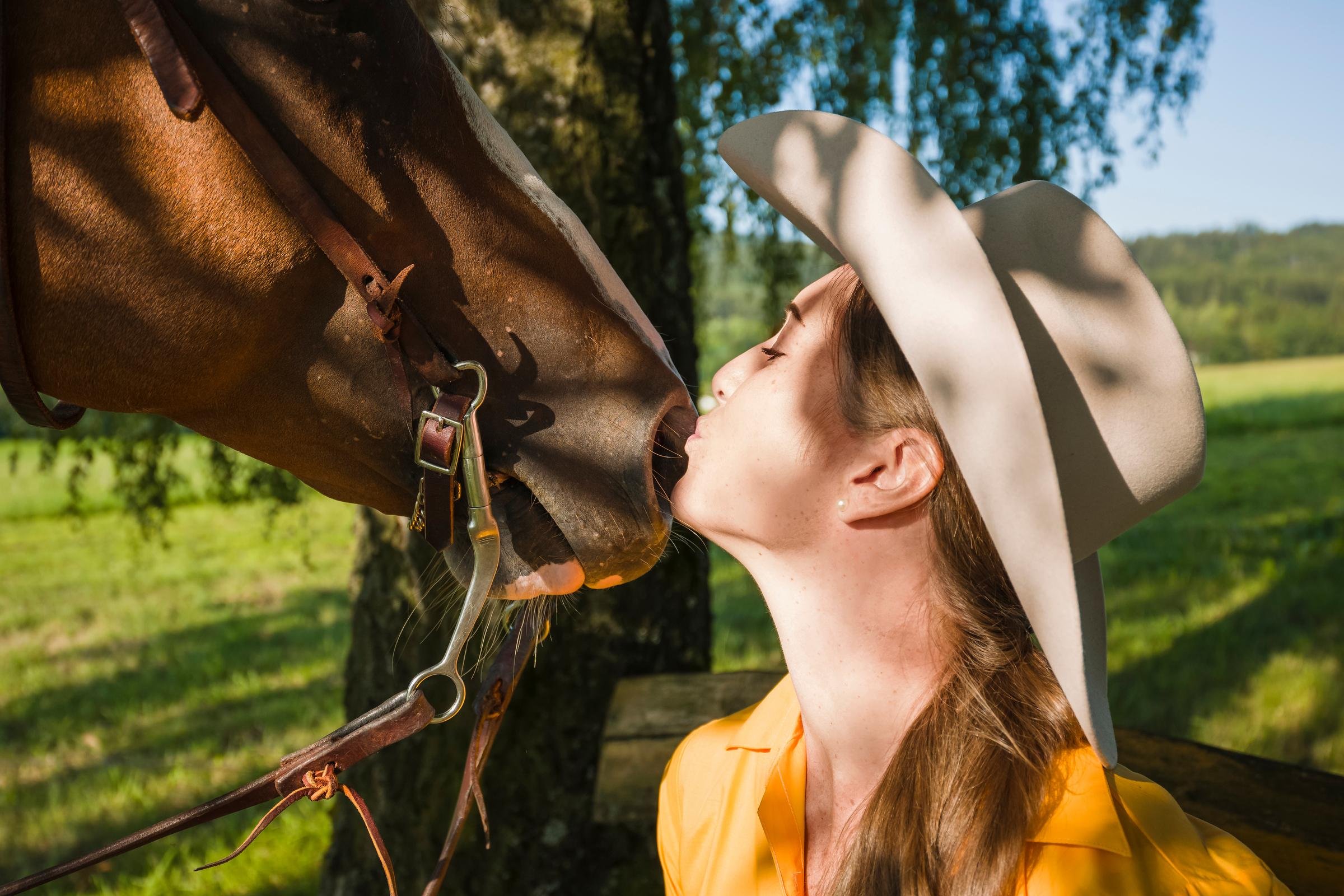 Ein Mensch mit Hut küsst ein Pferd auf der Wiese bei Sonnenlicht bei Aldiana Premium Cluburlaub