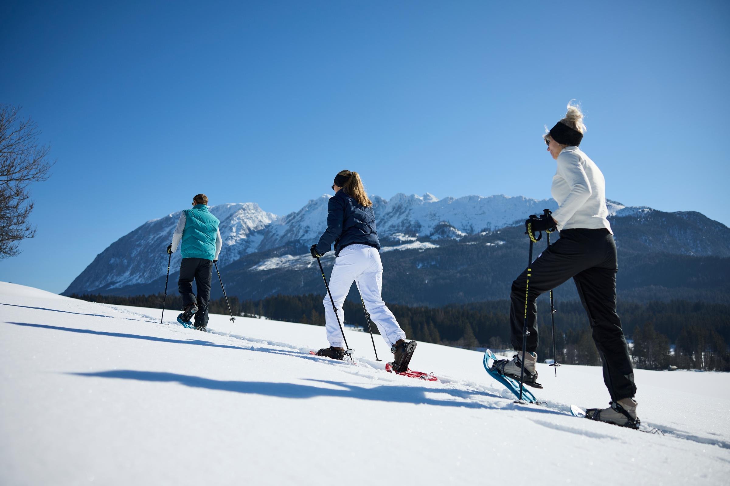 Drei Skifahrer beim Winterurlaub im Schnee mit Bergpanorama im Hintergrund