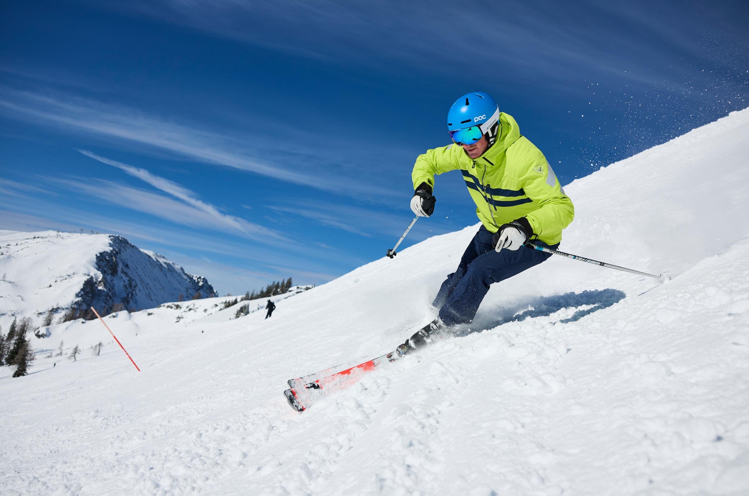 Skisportler fährt im Schnee einen Hang hinunter auf einer verschneiten Berg exponierte Landschaft