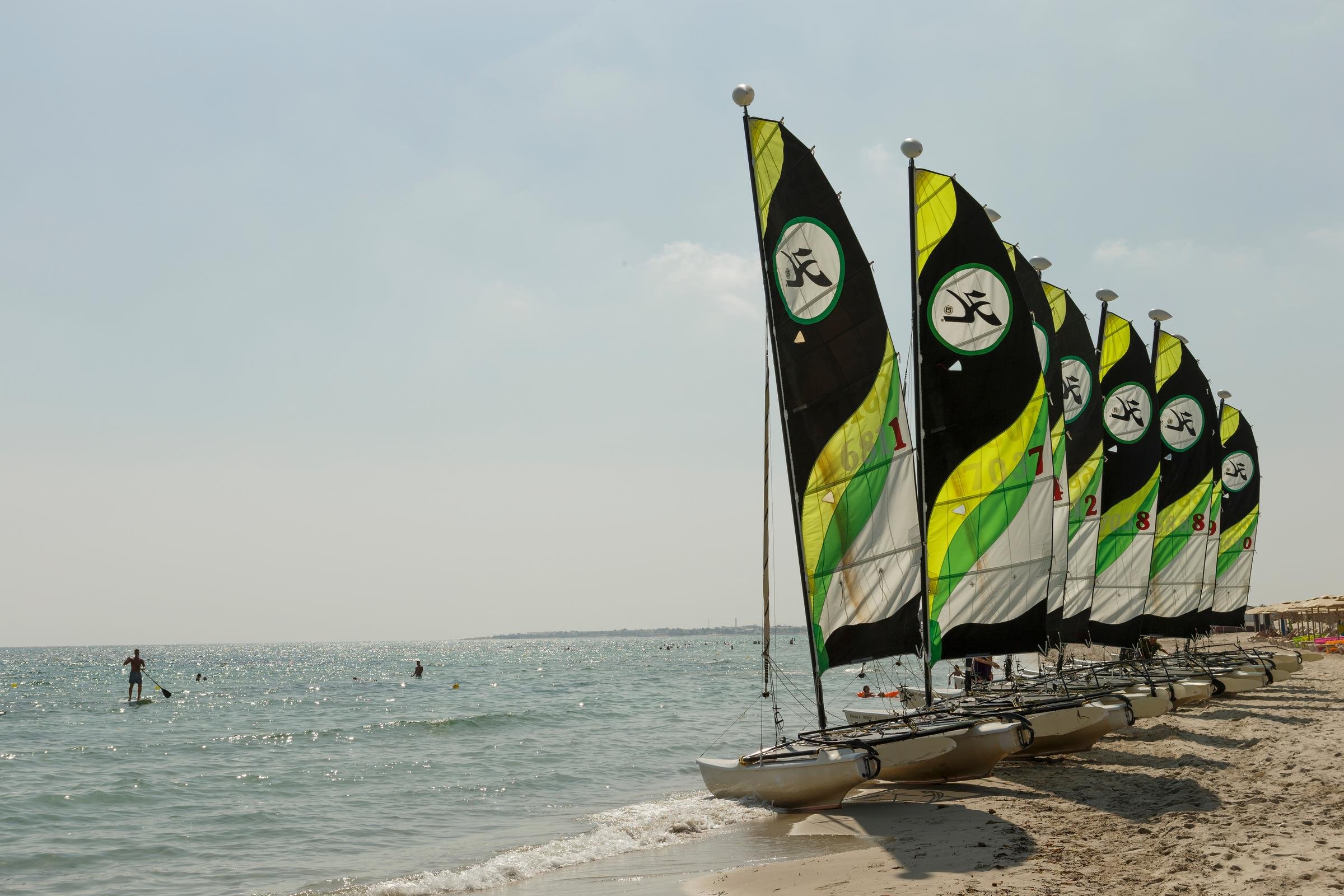 Bunte Opti-Yachten am Strand eines Premium Cluburlaubs bei Aldiana