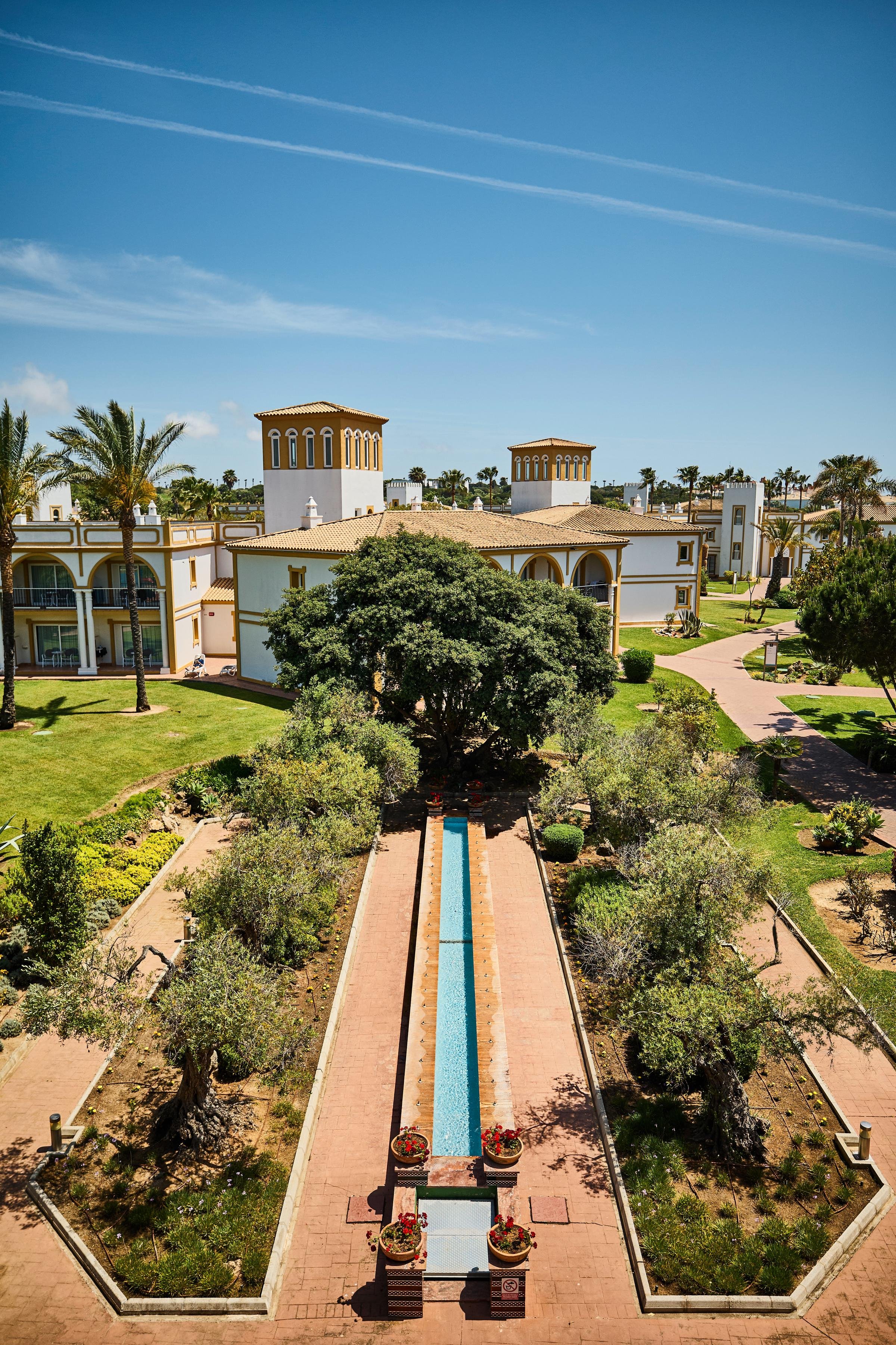 Schöne Gartenanlage mit Brunnen, Palmen und Blick auf elegante Hotelgebäude bei Aldiana