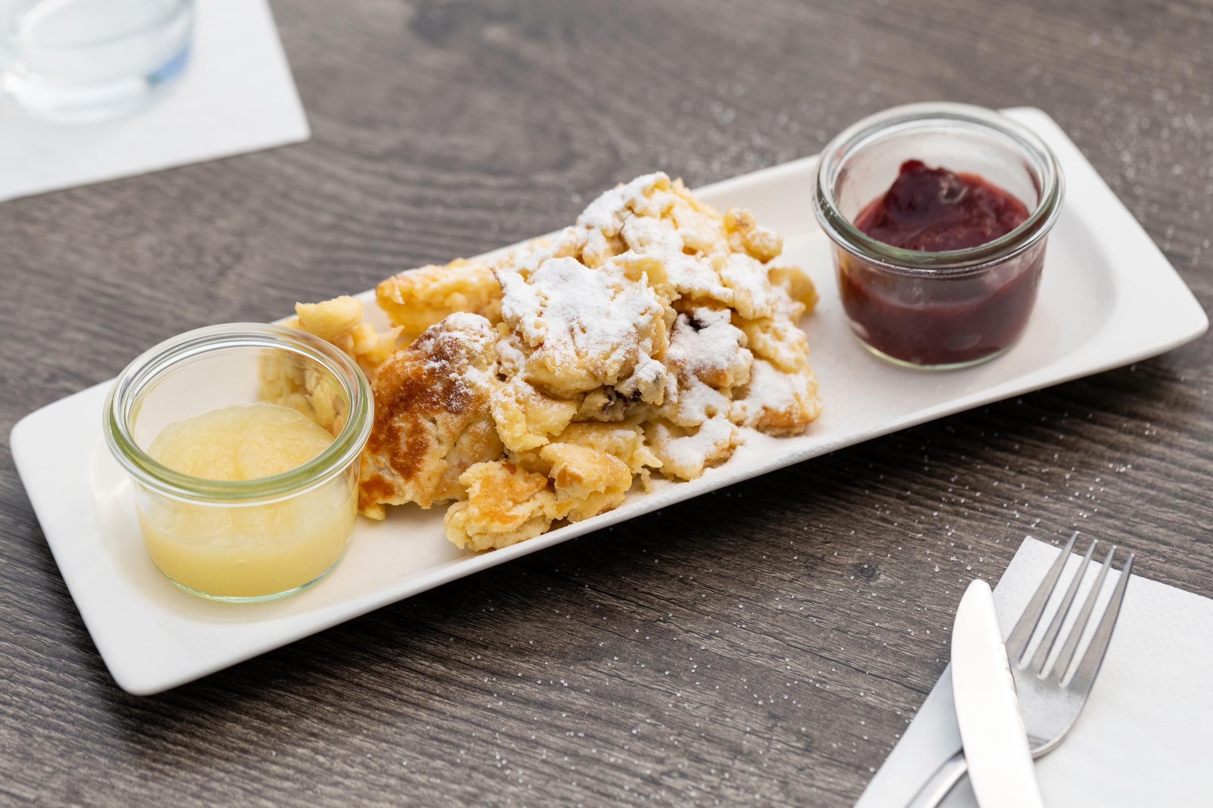 Ein Teller mit beschädigtem Donut, Puderzucker, Früchte und Beilagen auf hellem Porzellan