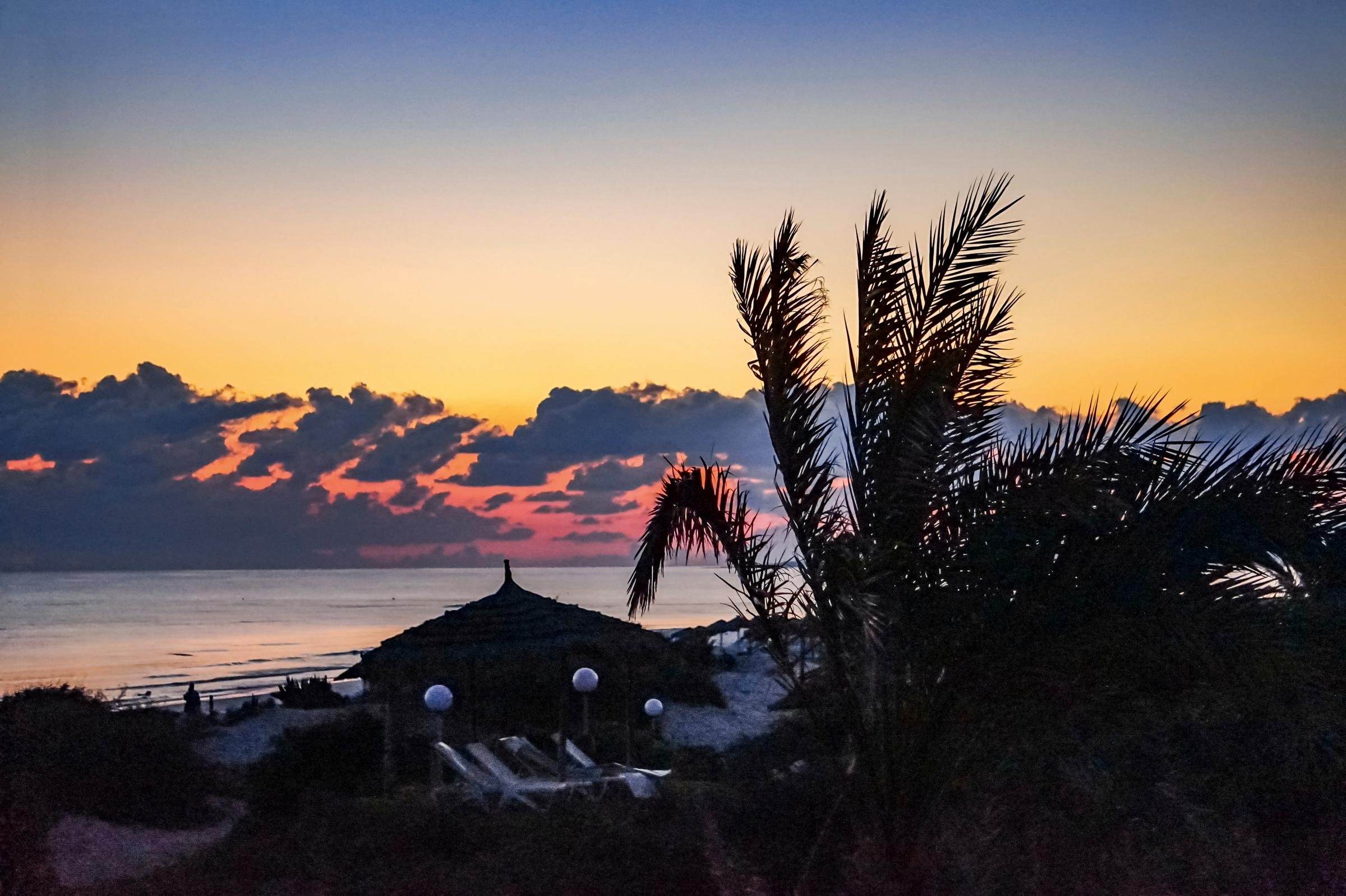 Sonnenuntergang über Strand mit Palmen und Strandhaus bei Aldiana, Premium Cluburlaub