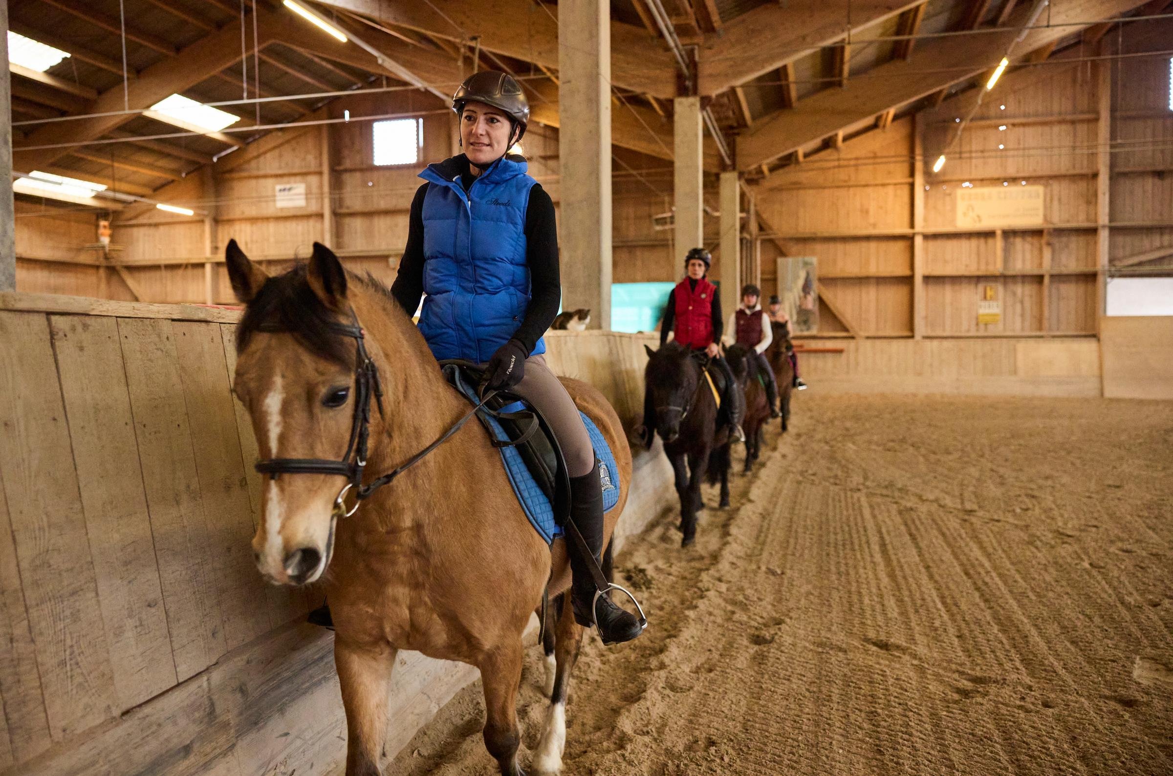 Junge Personen reiten in einer geräumigen Pferdestallhalle bei Aldiana, einem Premium Cluburlaubanbieter