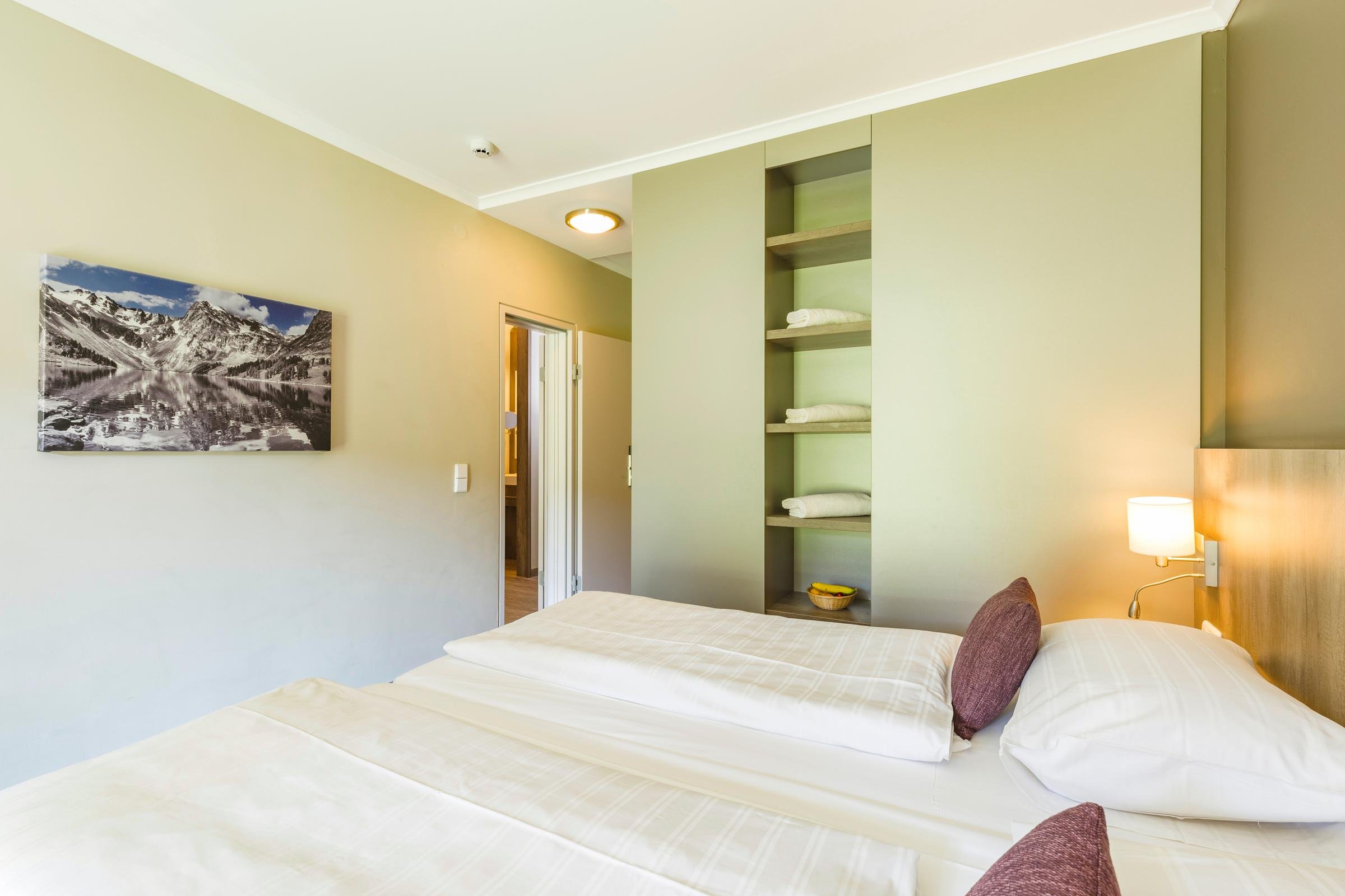 Dunkle Stoffkissen und dekorative Beleuchtung im modernen Hotelzimmer von Aldiana