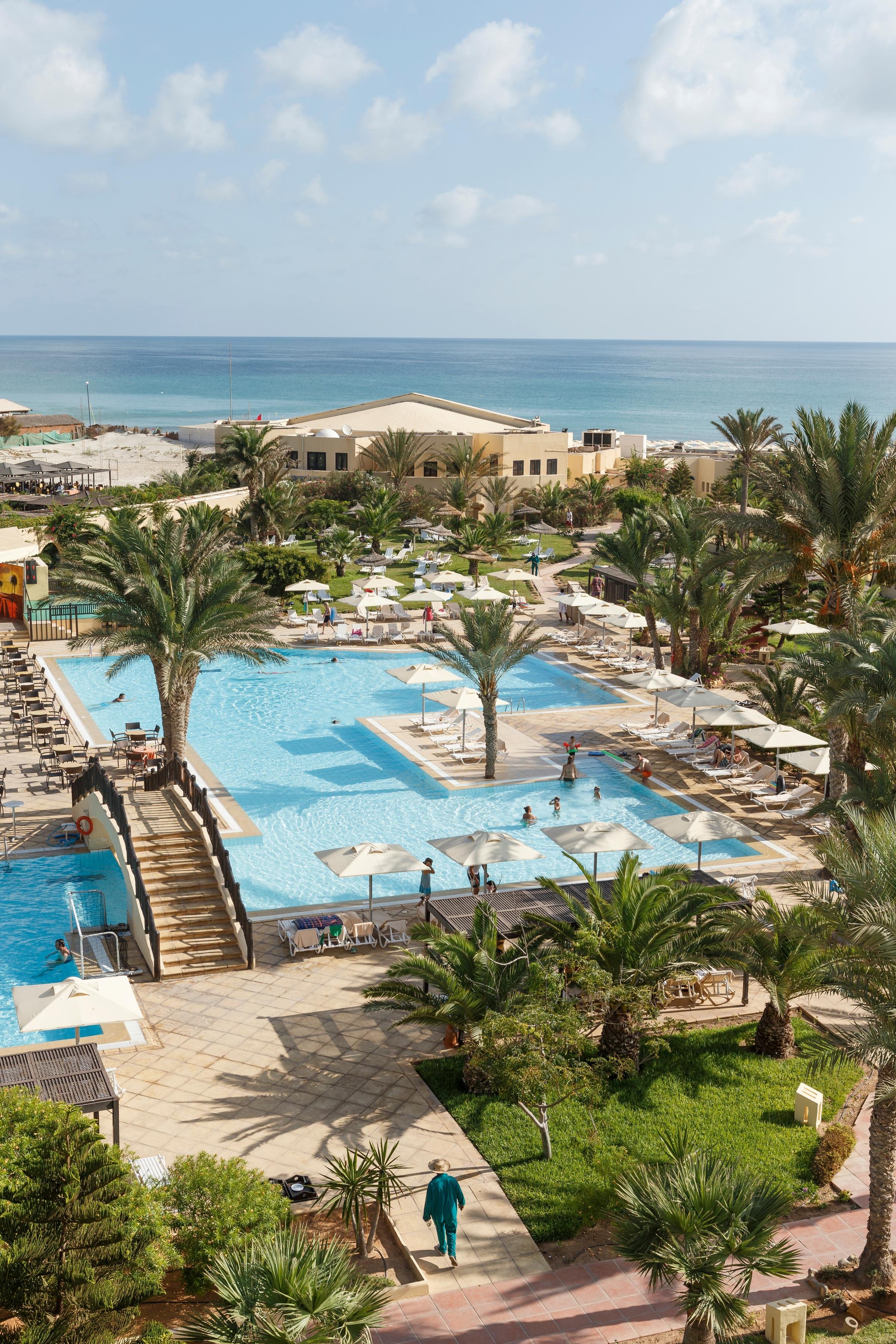 Blick auf den Premium Cluburlaub bei Aldiana mit Pool, Palmen und Meer im Hintergrund