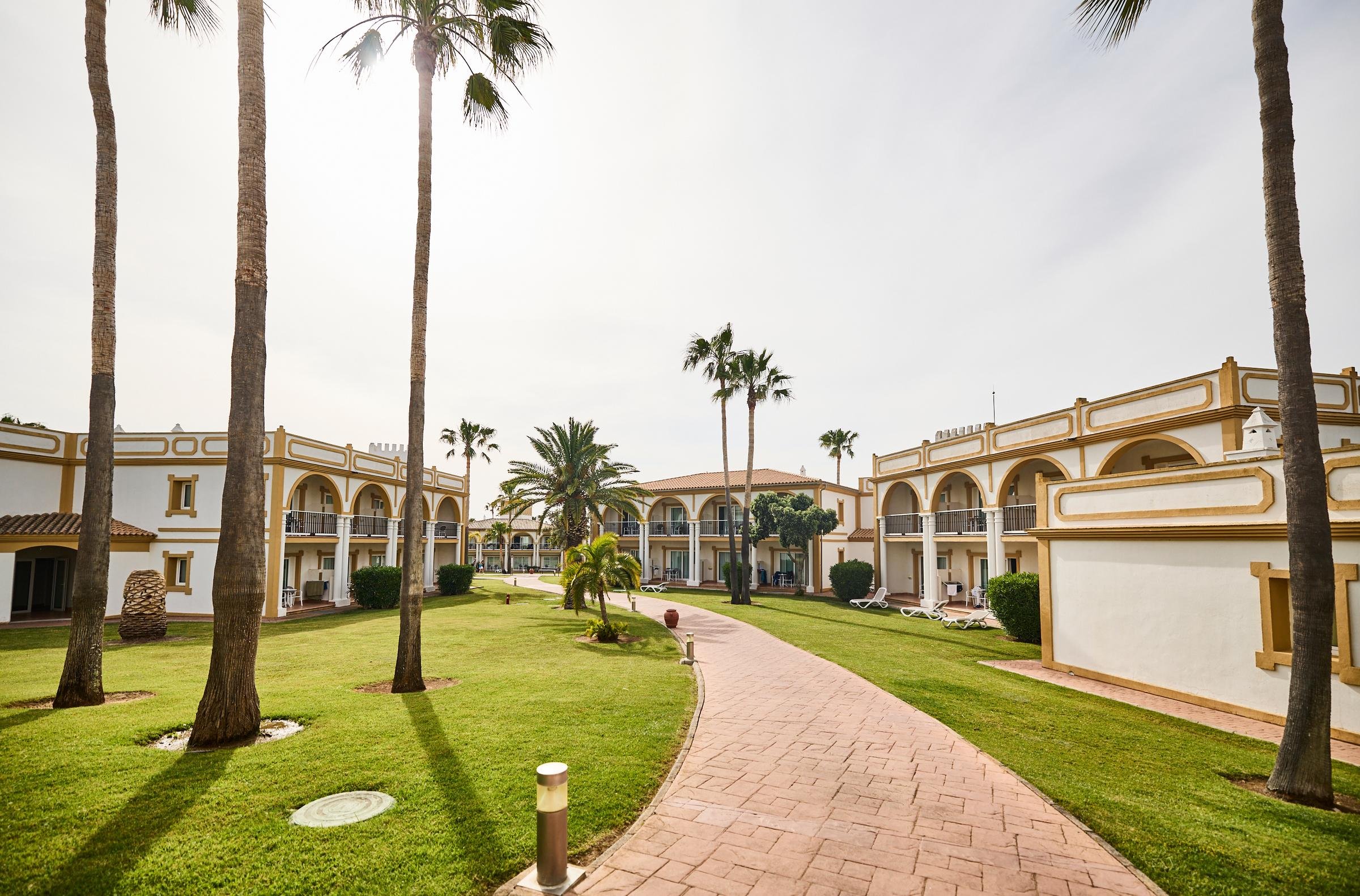 Schöne Hotelanlage bei Sonnenlicht mit Garten und Weg, ideal für Premium Cluburlaub