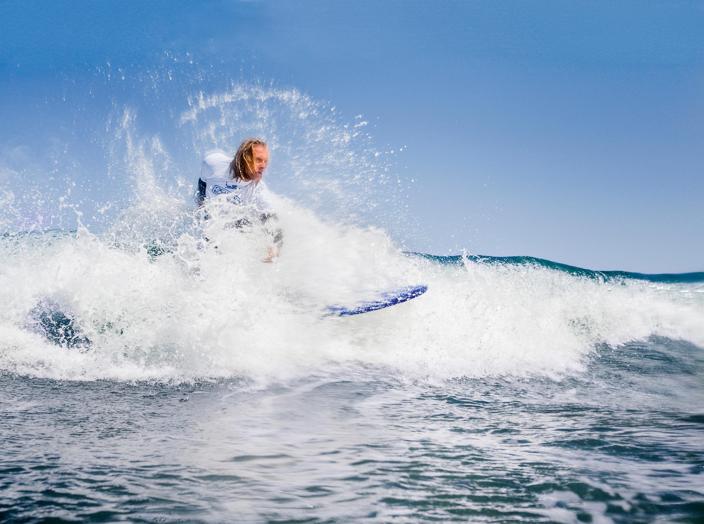 Mann surft auf Meerwellen, blaues Himmel, Premium Cluburlaub bei Aldiana