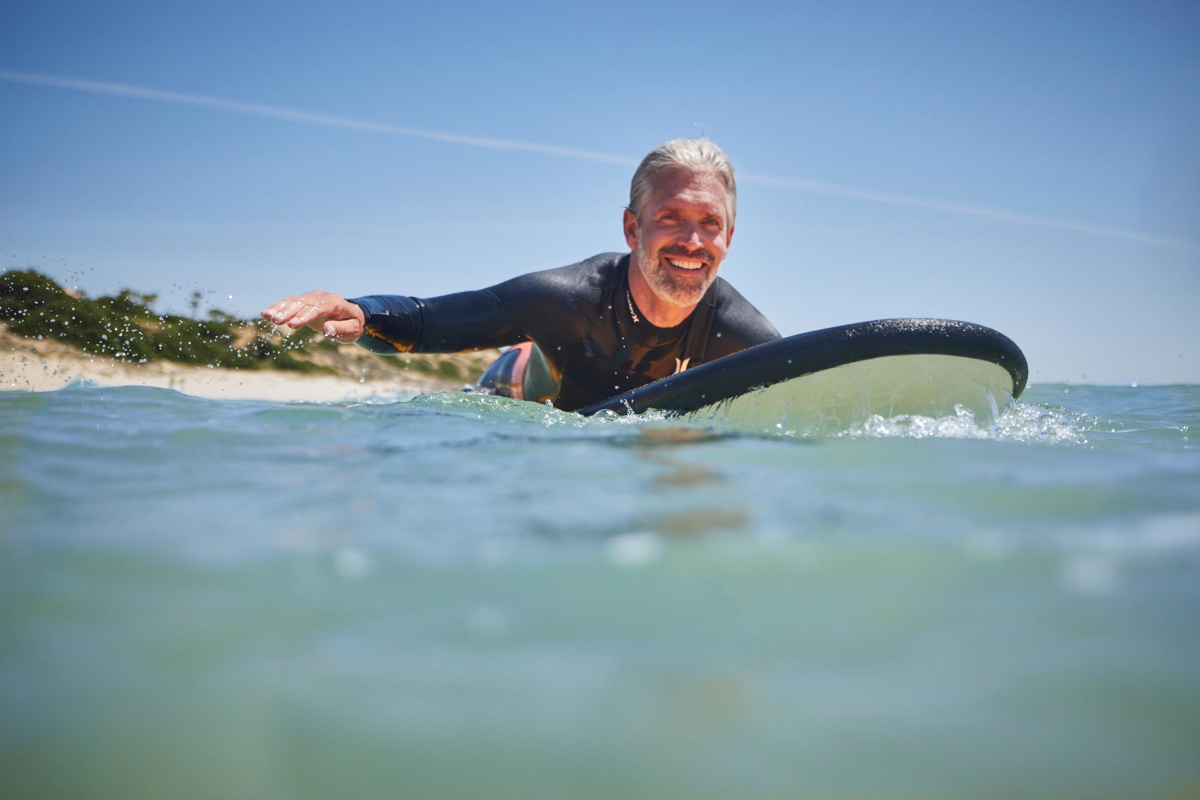 Mann beim Surfen im Meer, sonniger Tag, entspannter Premium Cluburlaub bei Aldiana