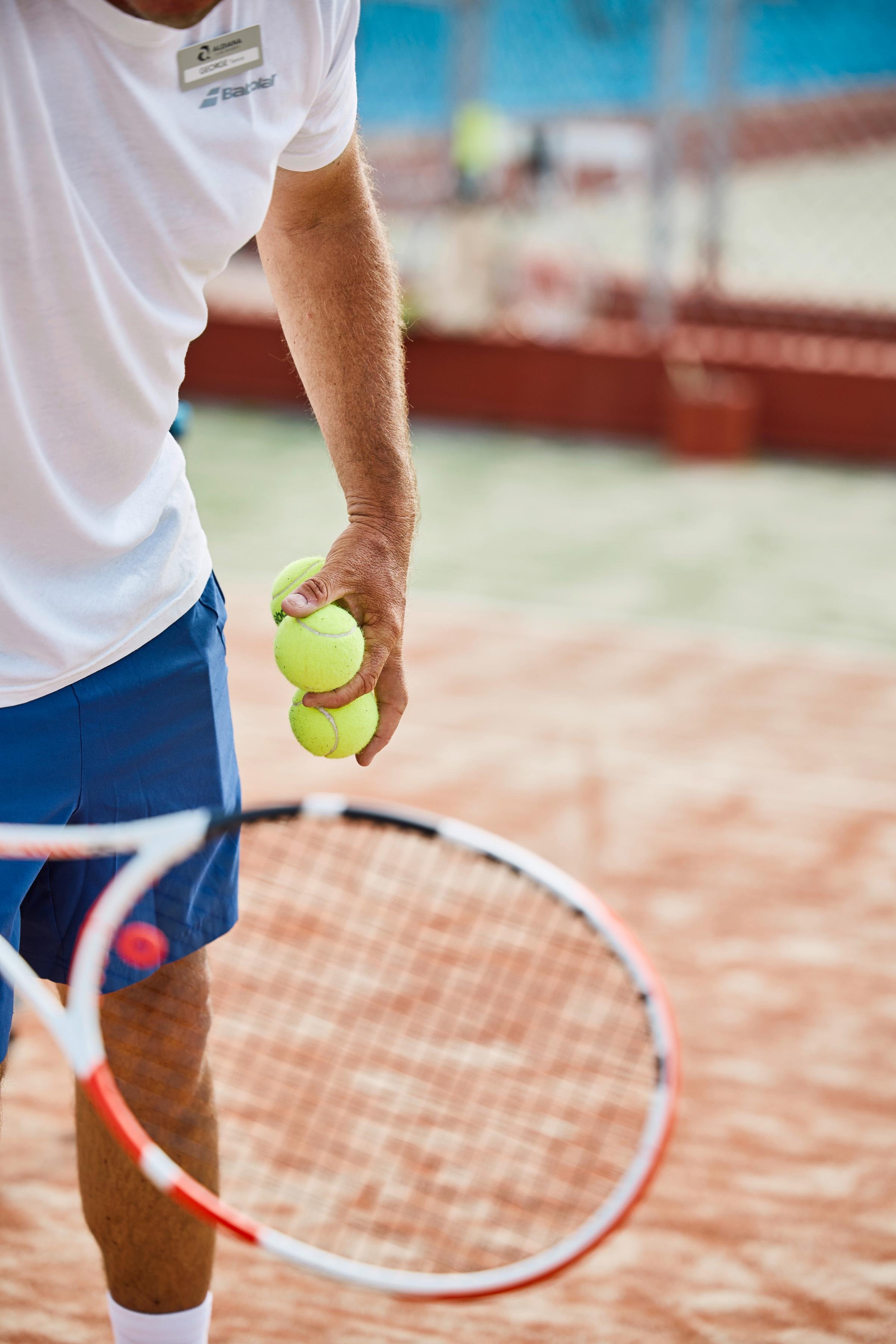 Frau mit Tennisballen auf dem Tennisplatz im hochwertigen Premium Cluburlaub von Aldiana