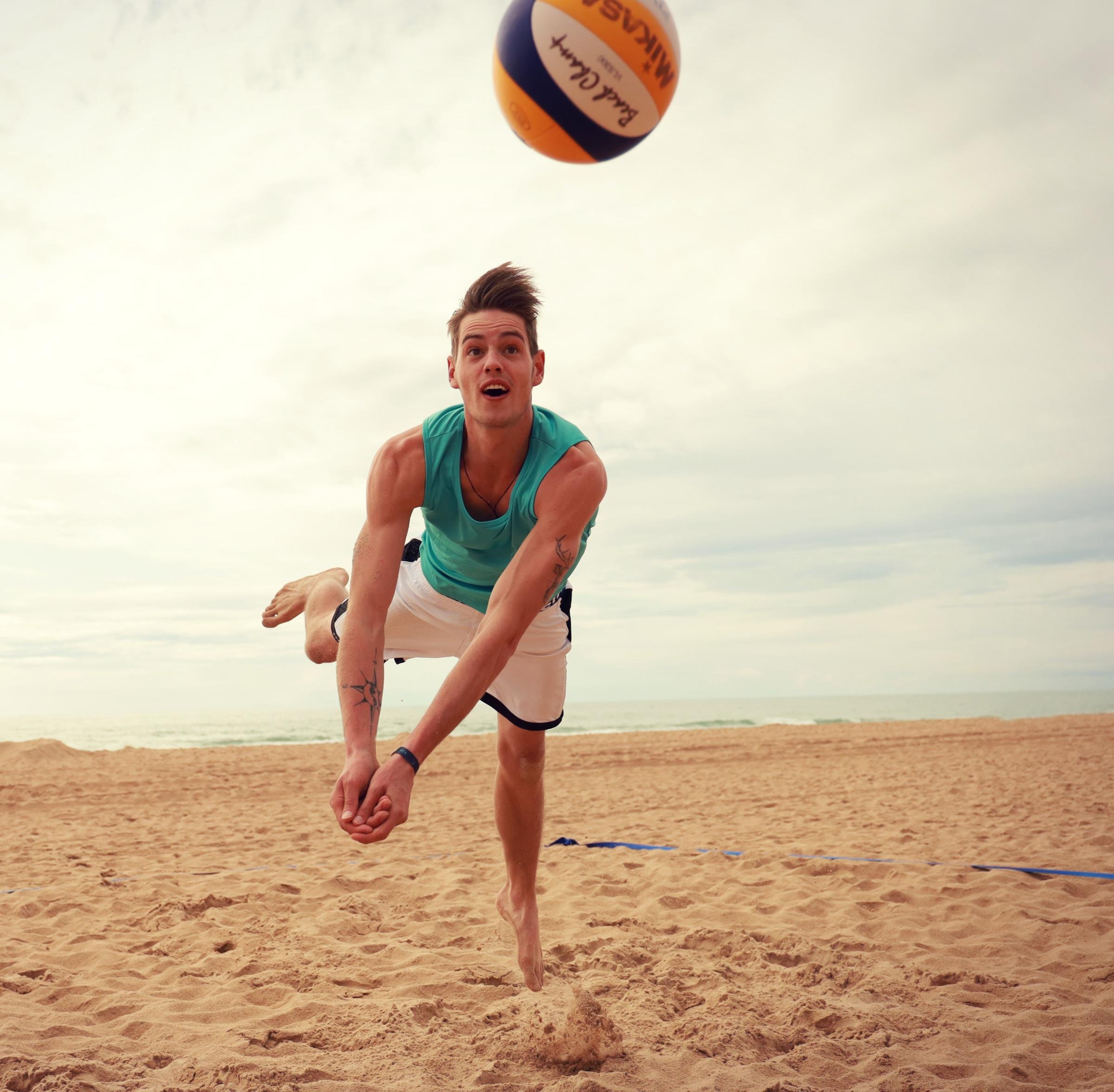 Mann spielt Volleyball am Strand bei Sonnenuntergang, Aktivitäten im Premium Cluburlaub