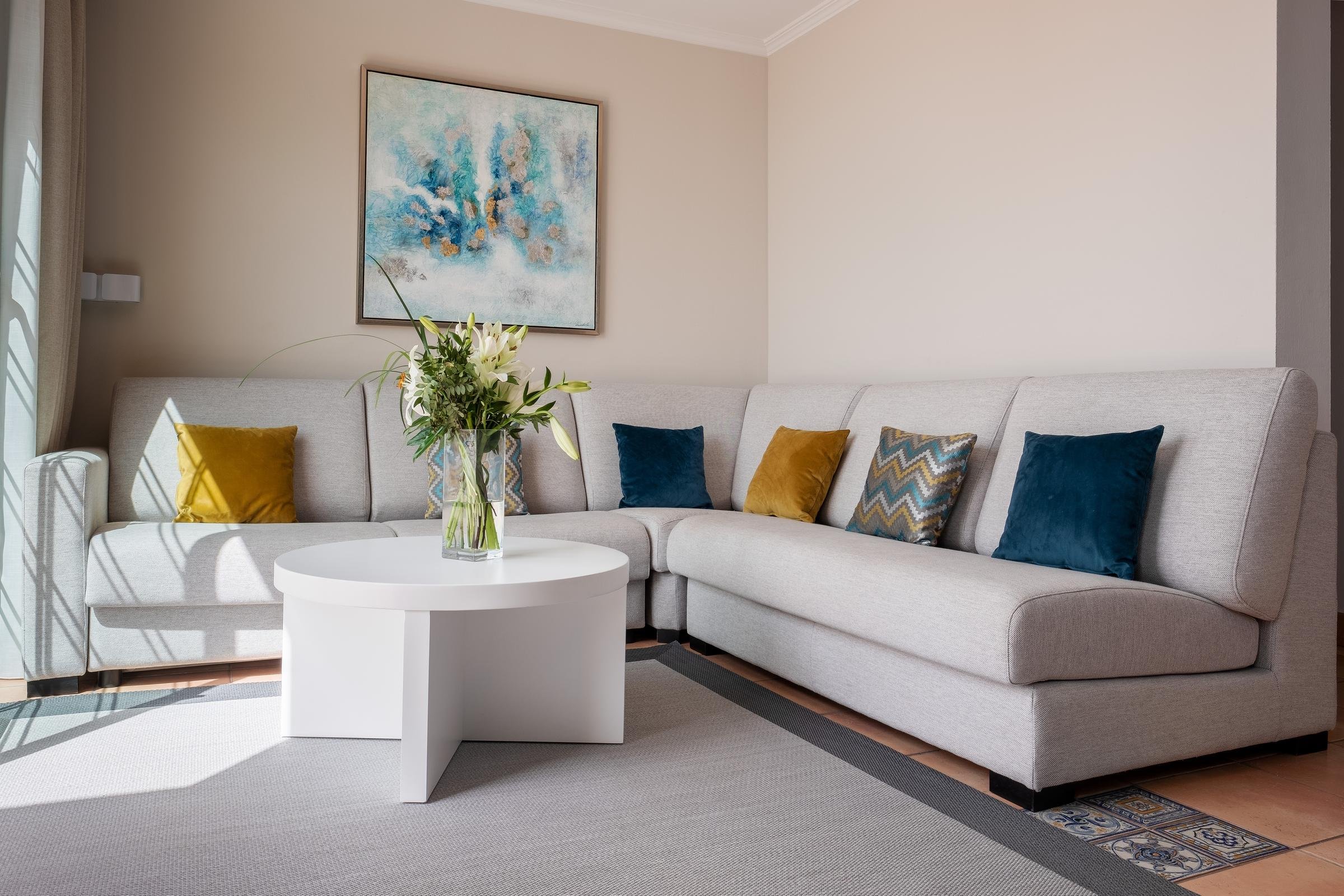 Gemütliches Wohnzimmer mit Sofa, Kissen, Pflanzen und abstrakter Wanddekoration