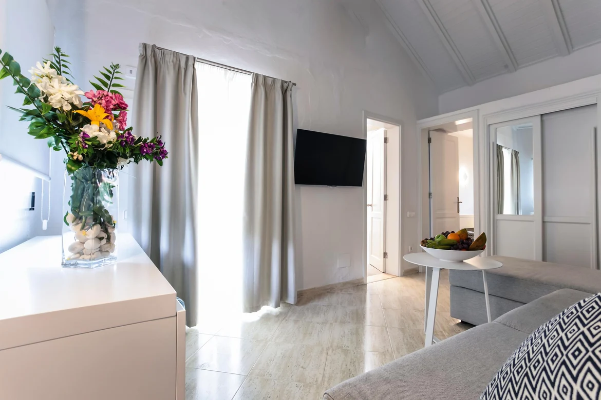 Elegantes Hotelzimmer mit Blumen, Fernseher und komfortabler Couch bei Aldiana Premium Cluburlaub