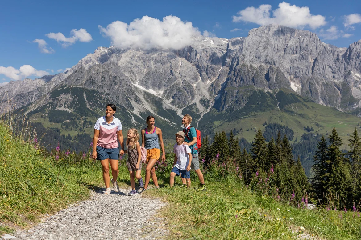 Eine Gruppe von Menschen wandert in einer Berglandschaft bei Sonnenschein