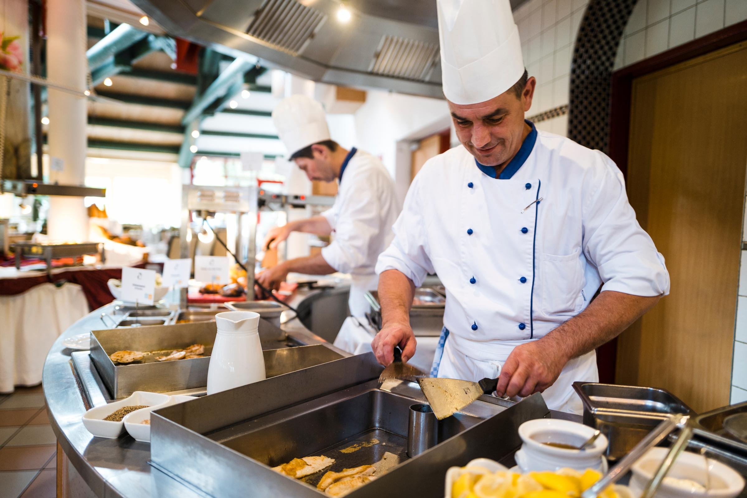 Koch im Restaurant bei Aldiana, bereitet Speisen in einer eleganten Atmosphäre vor