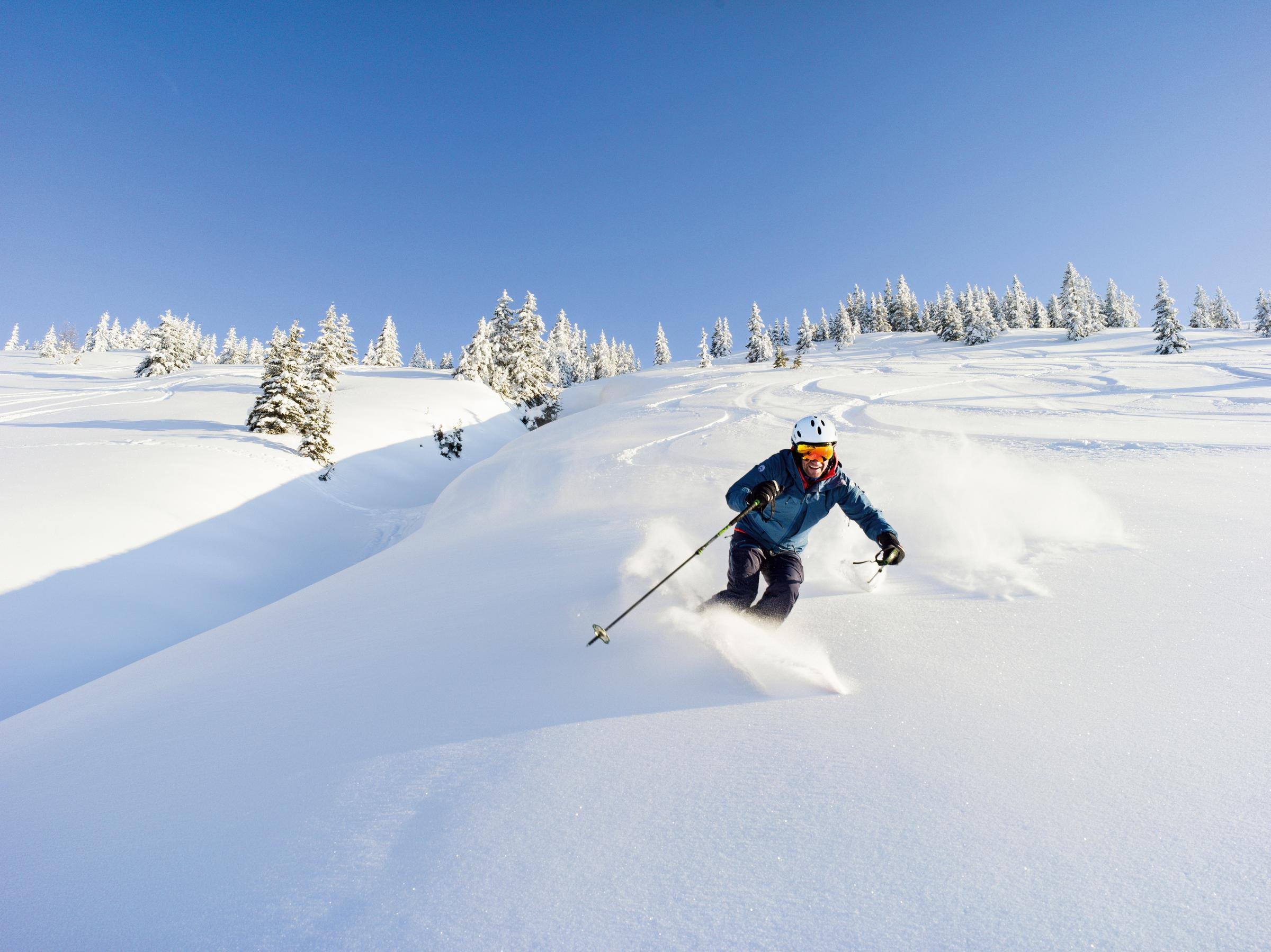Person beim Skifahren in tiefem Schnee in winterlicher Landschaft, Blauhimmel, Schneewald