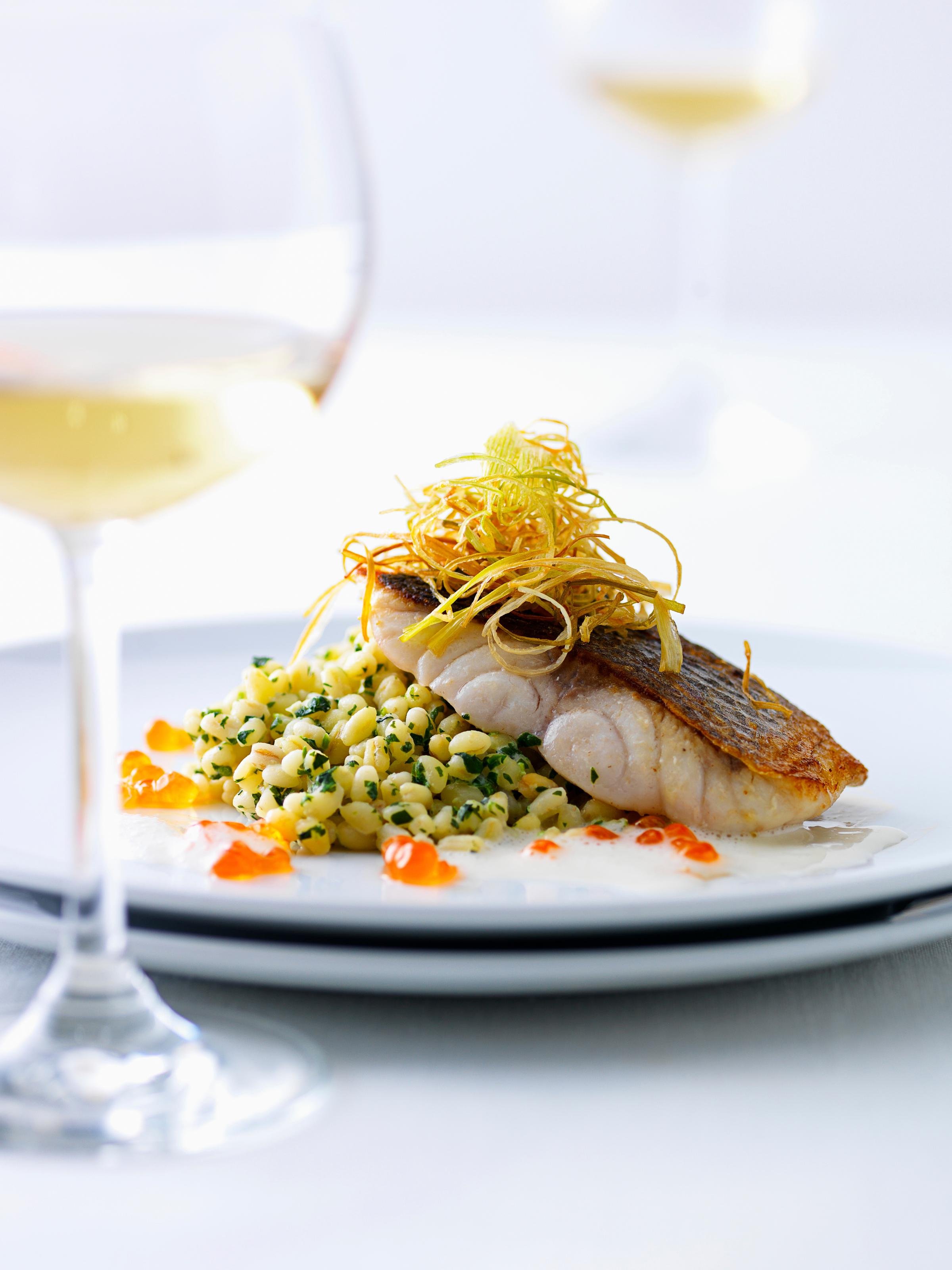 Ein elegantes Gericht mit Fisch, Pasta und Zitrus garnierte Präsentation für Premium Cluburlaub