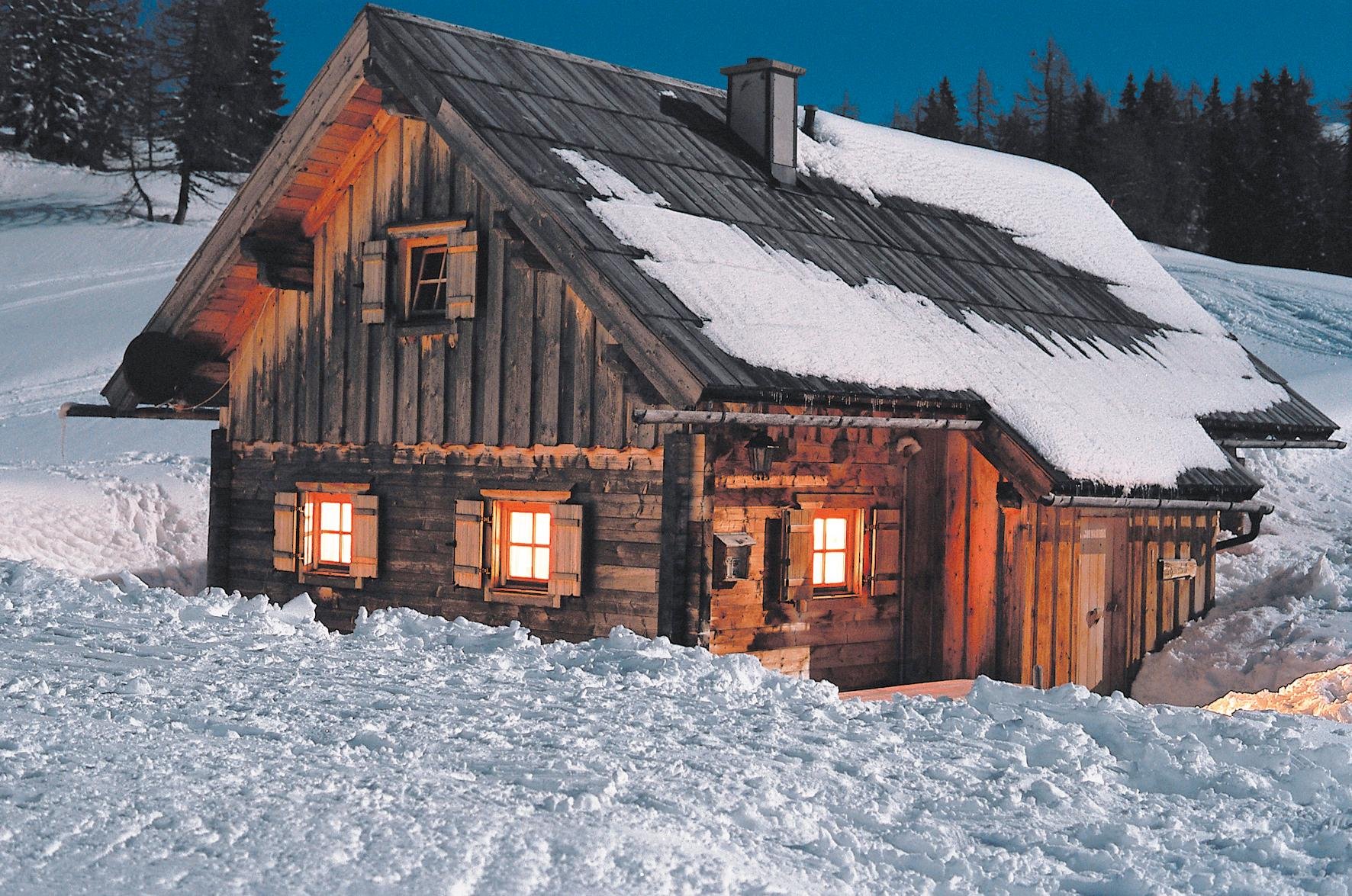 Ein gemütliches Holzhaus im verschneiten Winterland, ideal für Premium Cluburlaub bei Aldiana