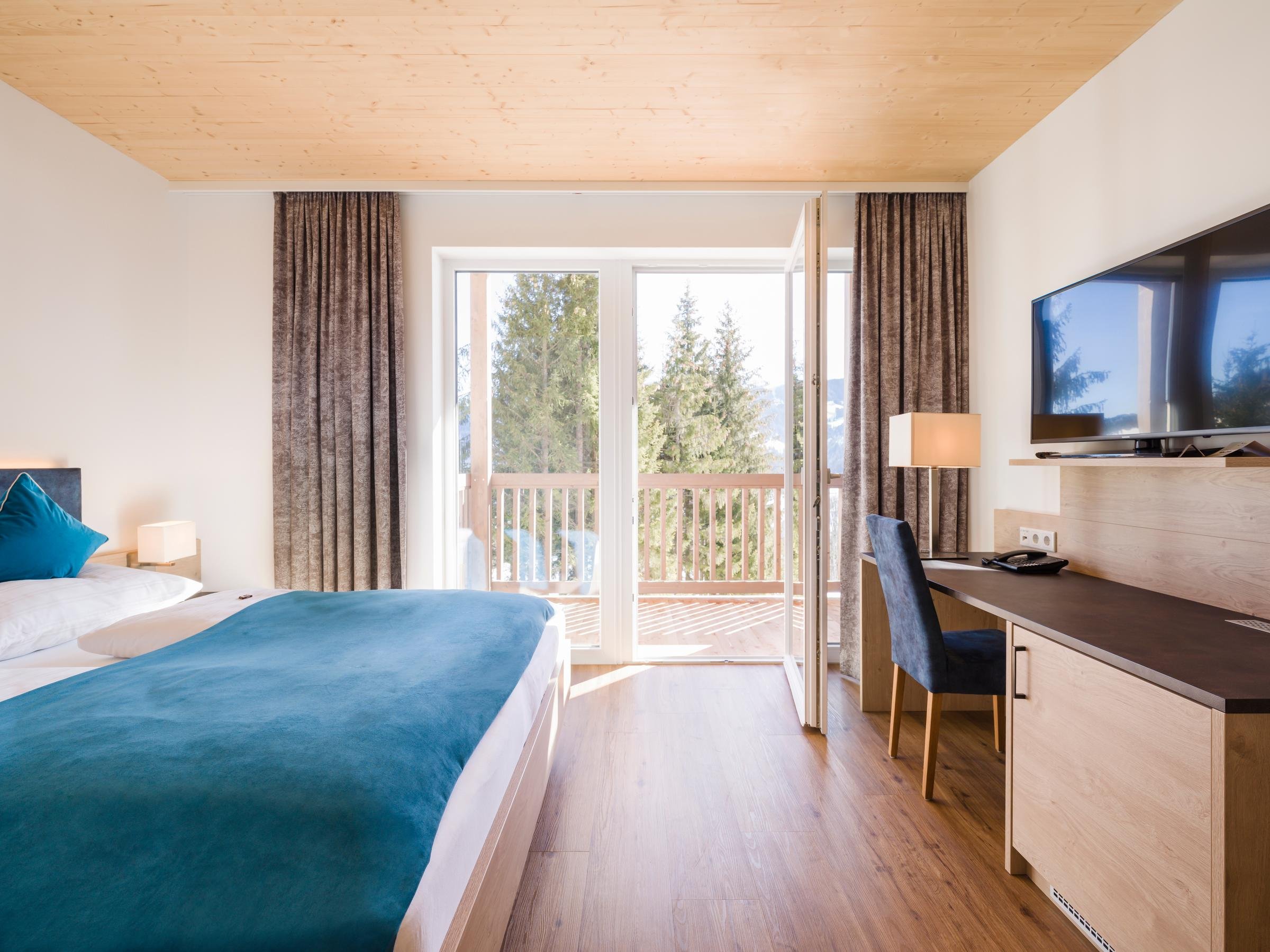 Blick in ein modernes Hotelzimmer bei Aldiana mit Balkon und Blick auf Natur.