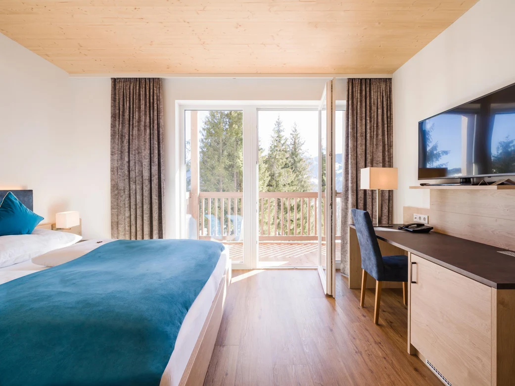 Blick in ein modernes Hotelzimmer bei Aldiana mit Balkon und Blick auf Natur.