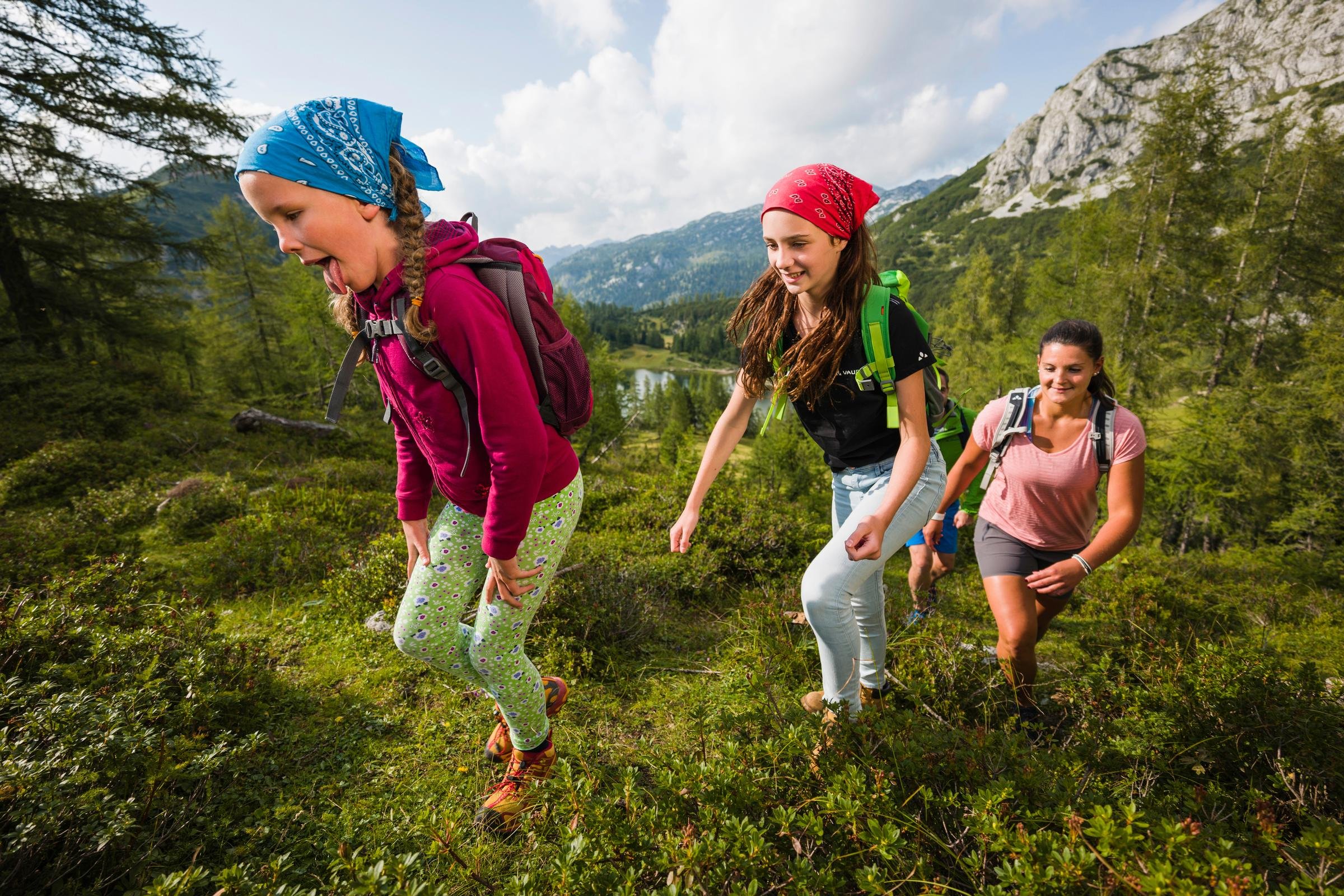 Vier Frauen beim Wandern in der Natur, eines der Bilder unkalibriert, alle mit Rucksack