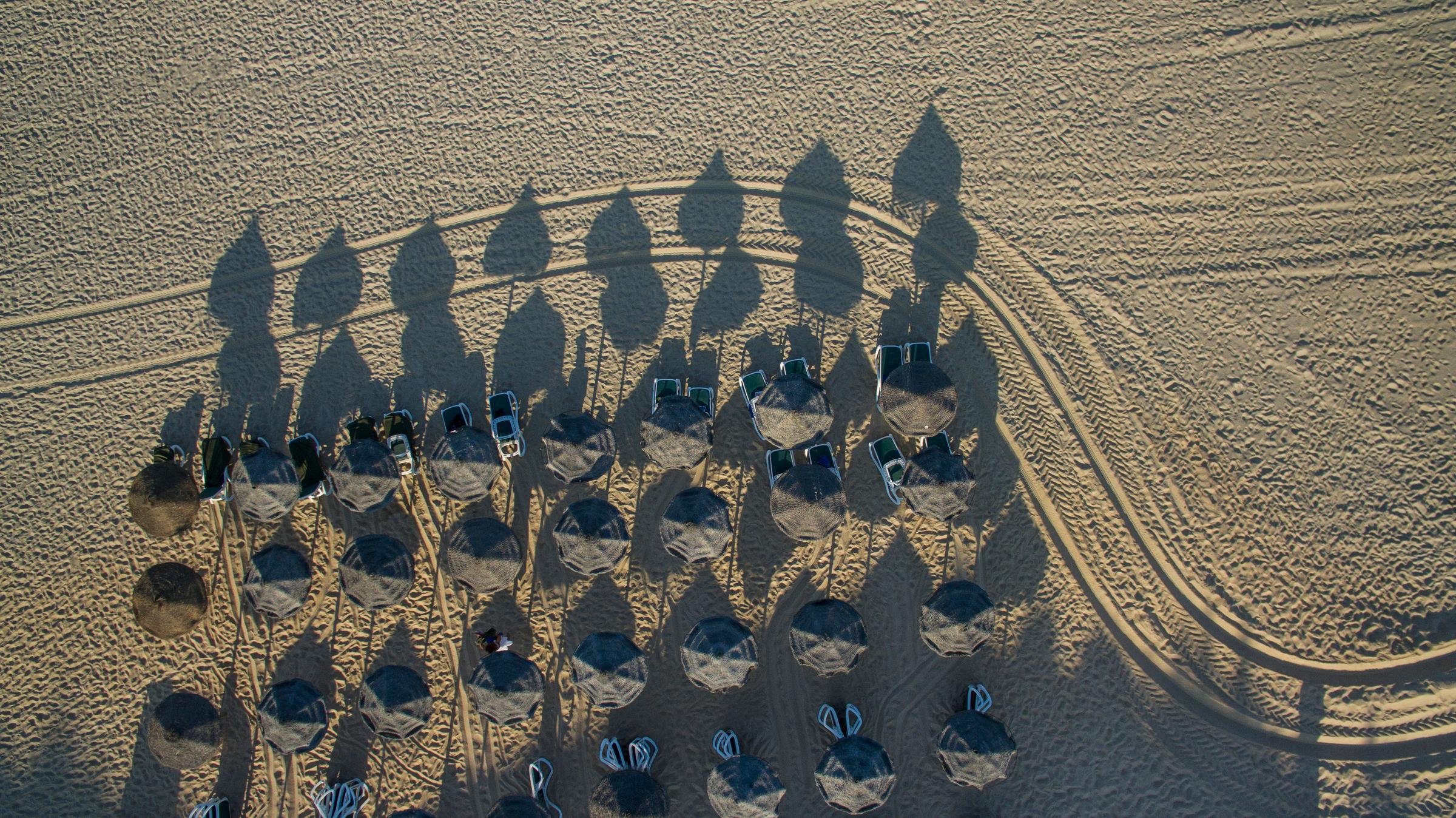 Blick aus der Luft auf Strand mit Sonnenschirmen und Liegen bei Aldiana Urlaubsort