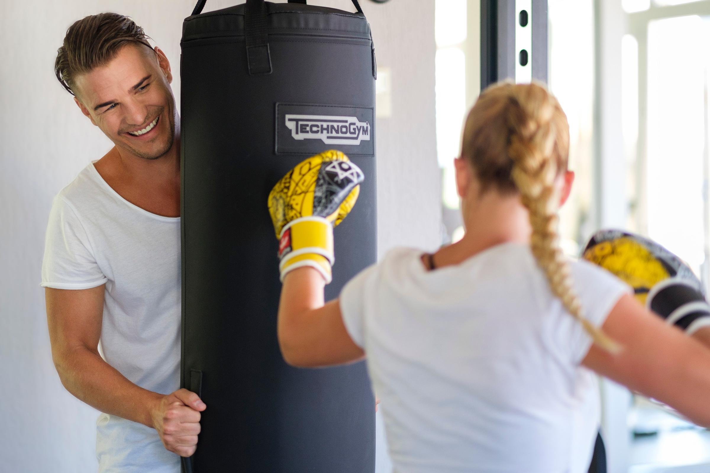 Trainerin schlägt Boxsack im Fitnessraum bei Aldiana vor Outdoor-Urlaub