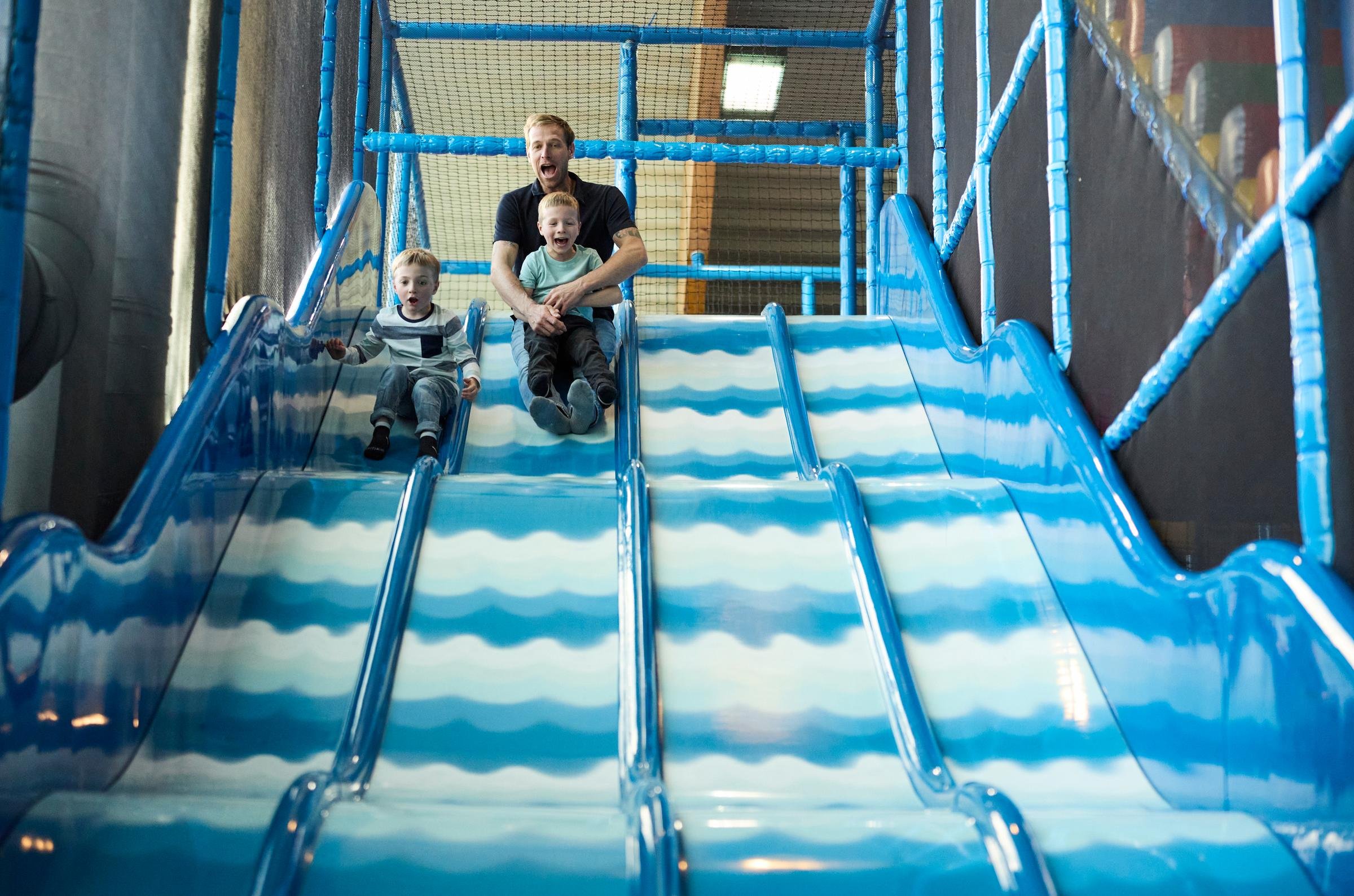 Kinder rutschen auf blauer Wasser-Rutsche in einem Aldiana Freizeitbereich.