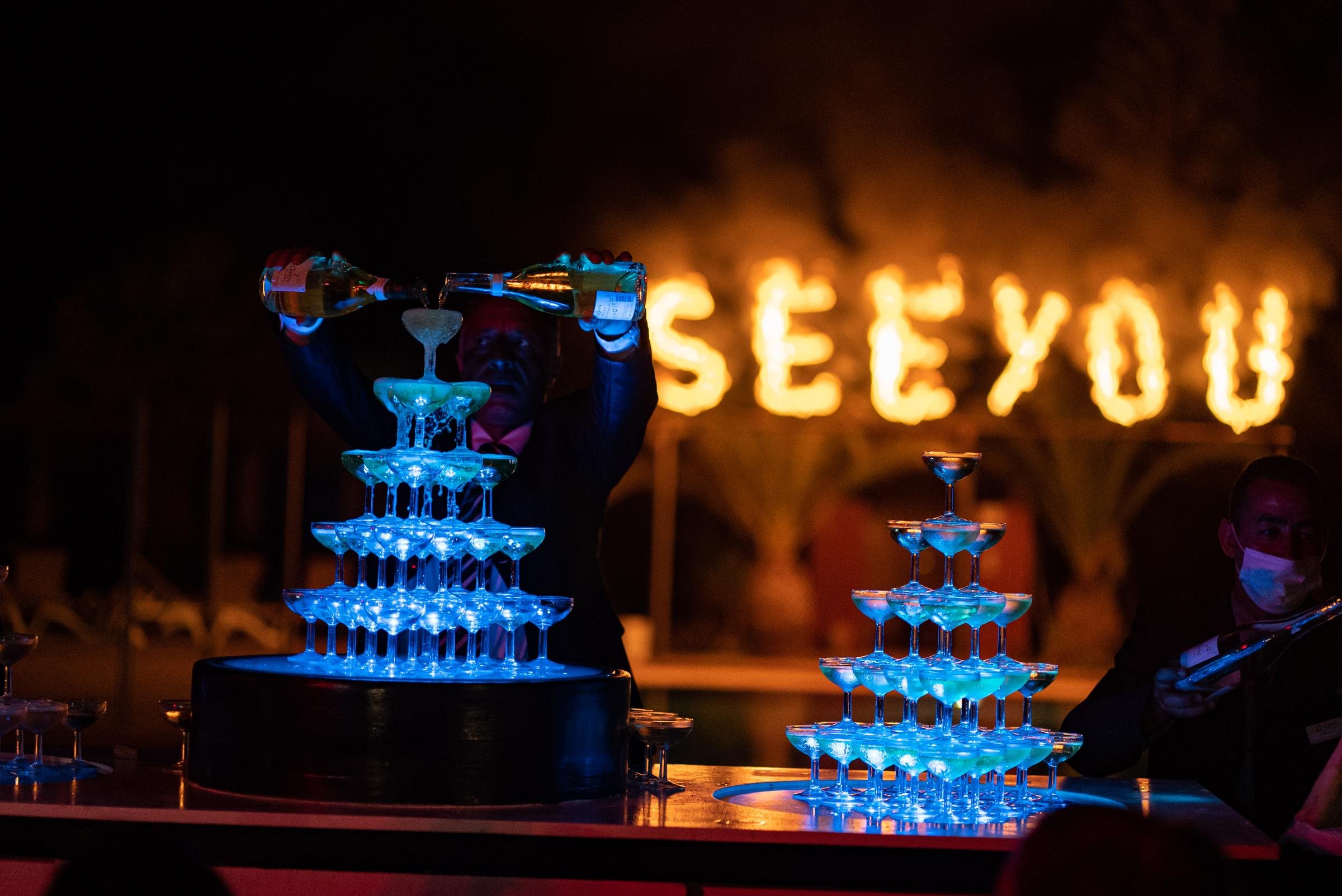 Zwei Sektgläser auf obere Etagen, Feuerwerk im Hintergrund mit leuchtender Aldiana Schrift