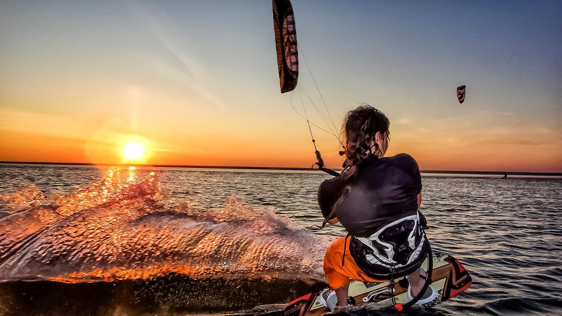 Ein Junge surft bei Sonnenuntergang auf dem Wasser, Spaß beim Wassersport bei Aldiana