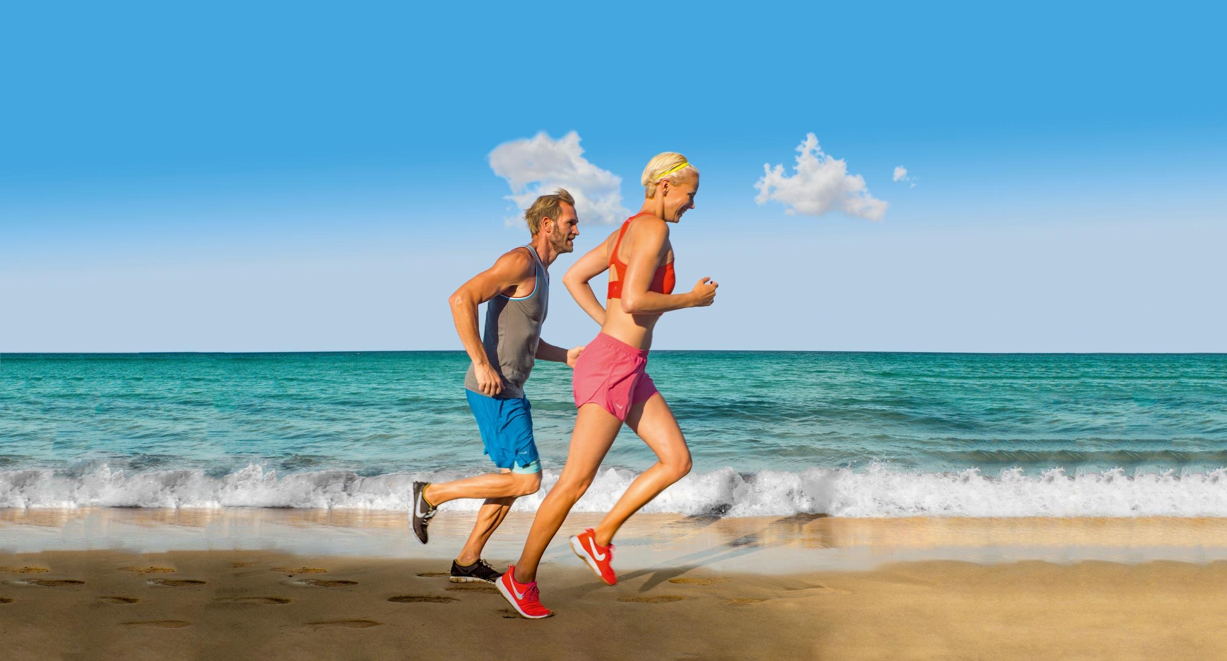 Zwei Personen laufen am Strand entlang bei Sonnenlicht, symbolisiert aktiven Premium Cluburlaub