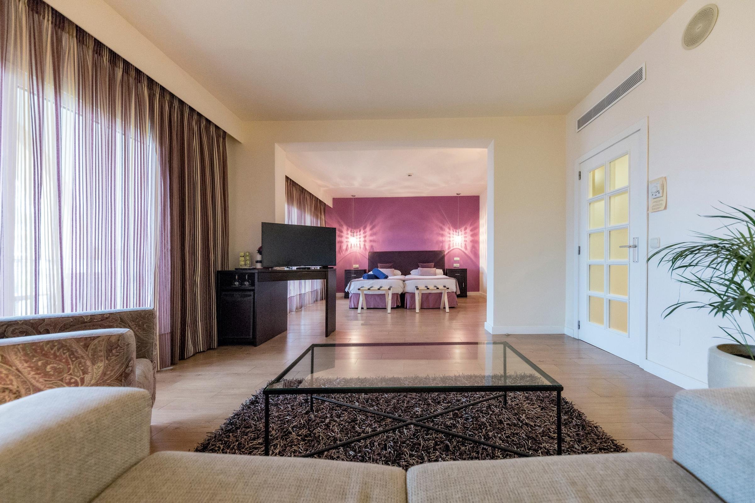 Innenraum eines modernen Hotels mit Fernseher, Sofa, Tisch und Blick auf den Schlafbereich