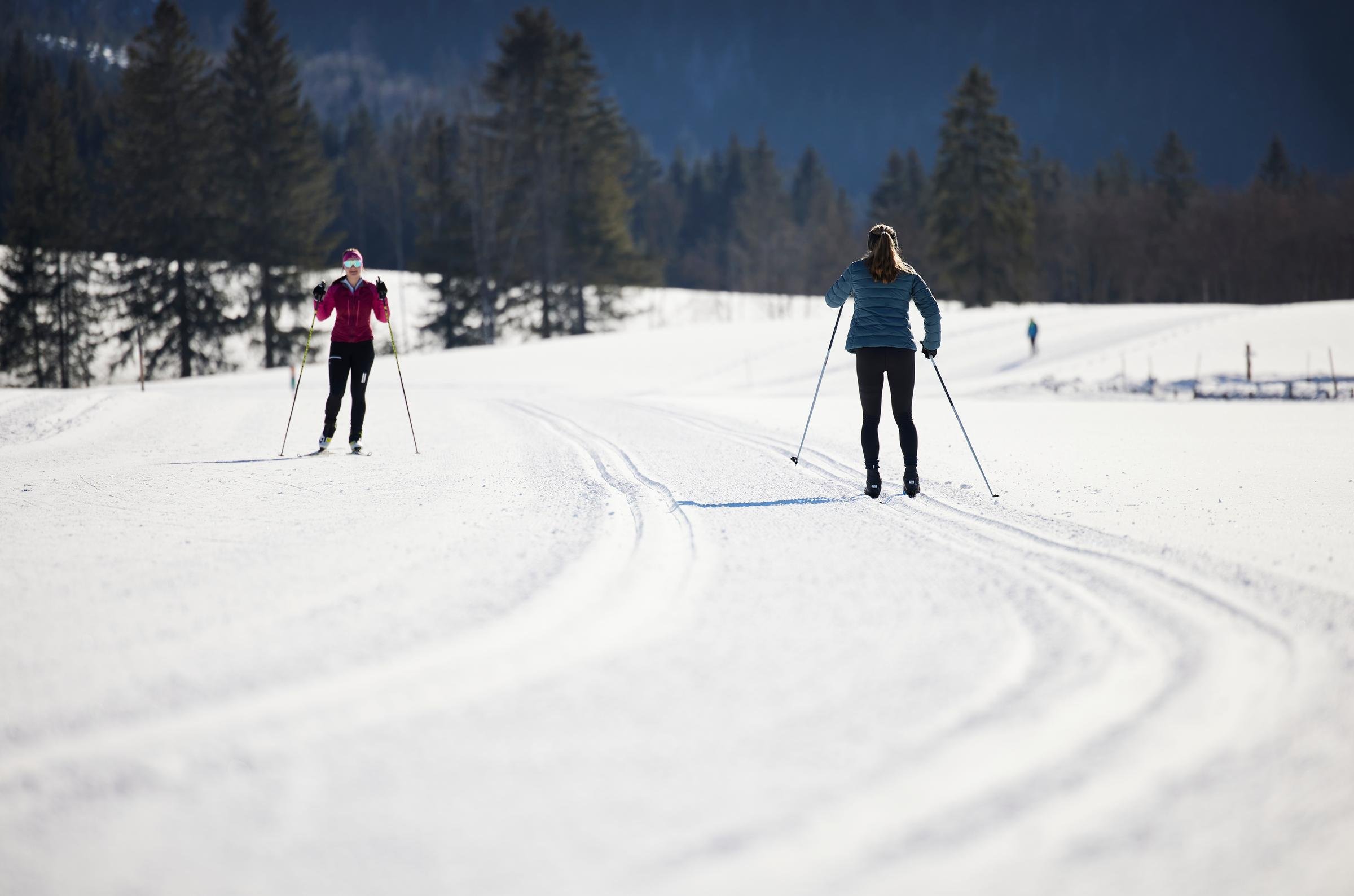 Zwei Frauen beim Skilanglauf im Schnee vor Waldlandschaft in einer Premium Winterreise von Aldiana