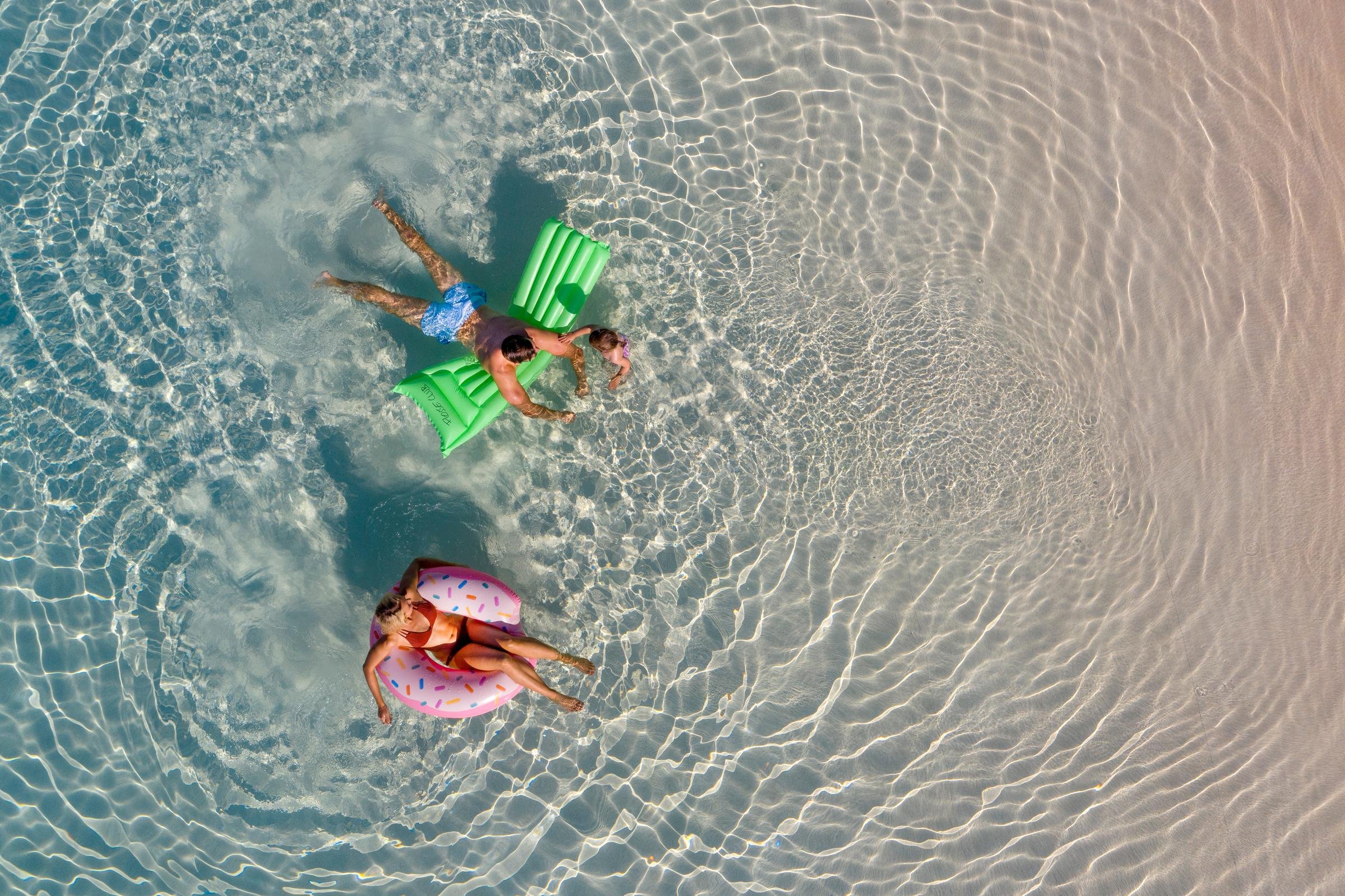Zwei Kinder schwimmen mit Luftmatratzen im klaren Wasser eines Premium Cluburlaubs von Aldiana
