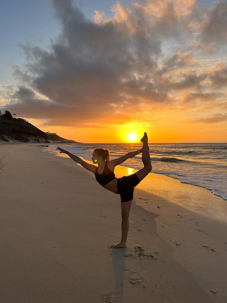 Person beim Yoga am Strand bei Sonnenuntergang, ideal für Premium Urlaub bei Aldiana