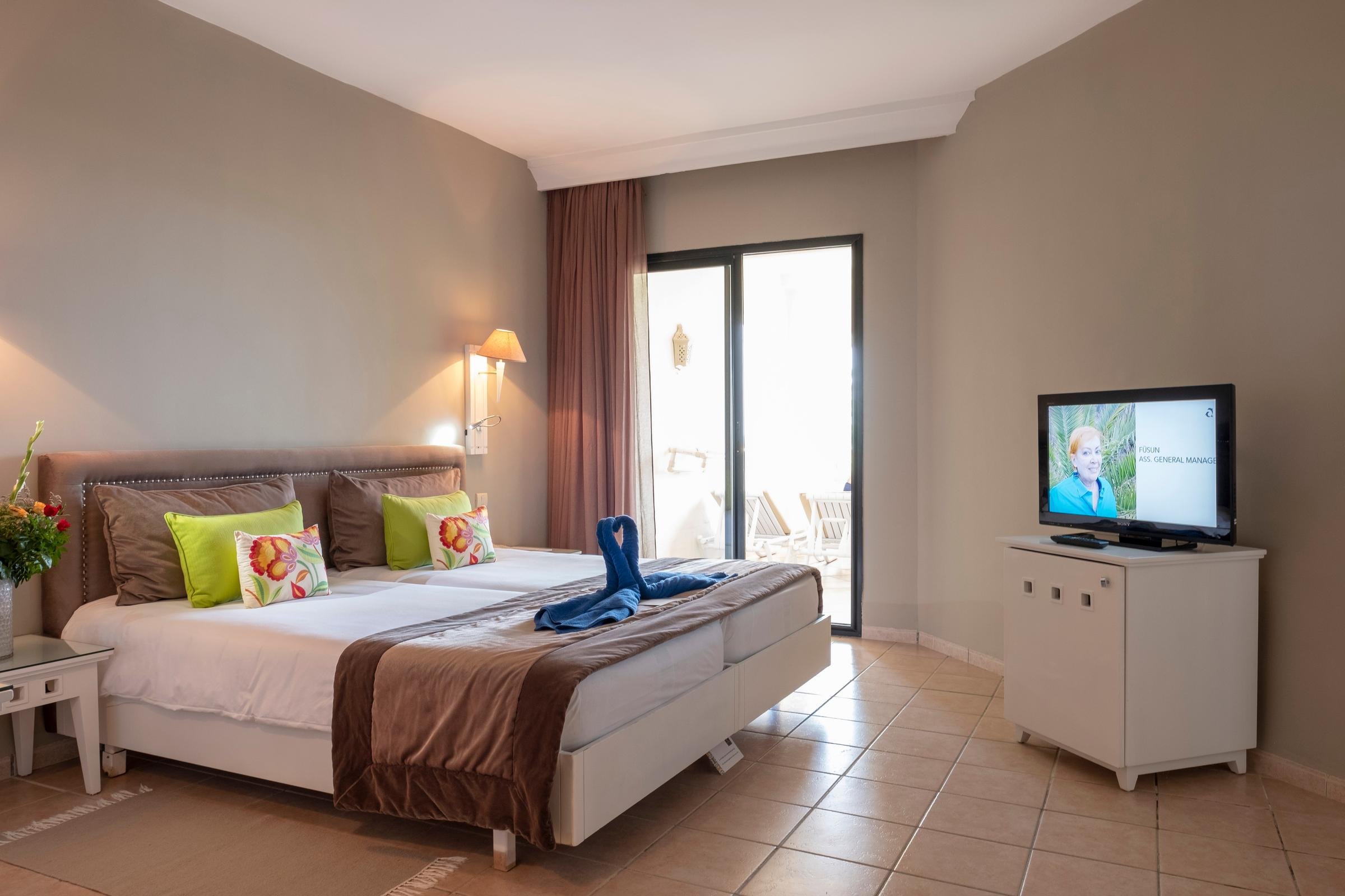 Ein modern eingerichtetes Hotelzimmer mit großem Bett, TV und Balkon bei Aldiana