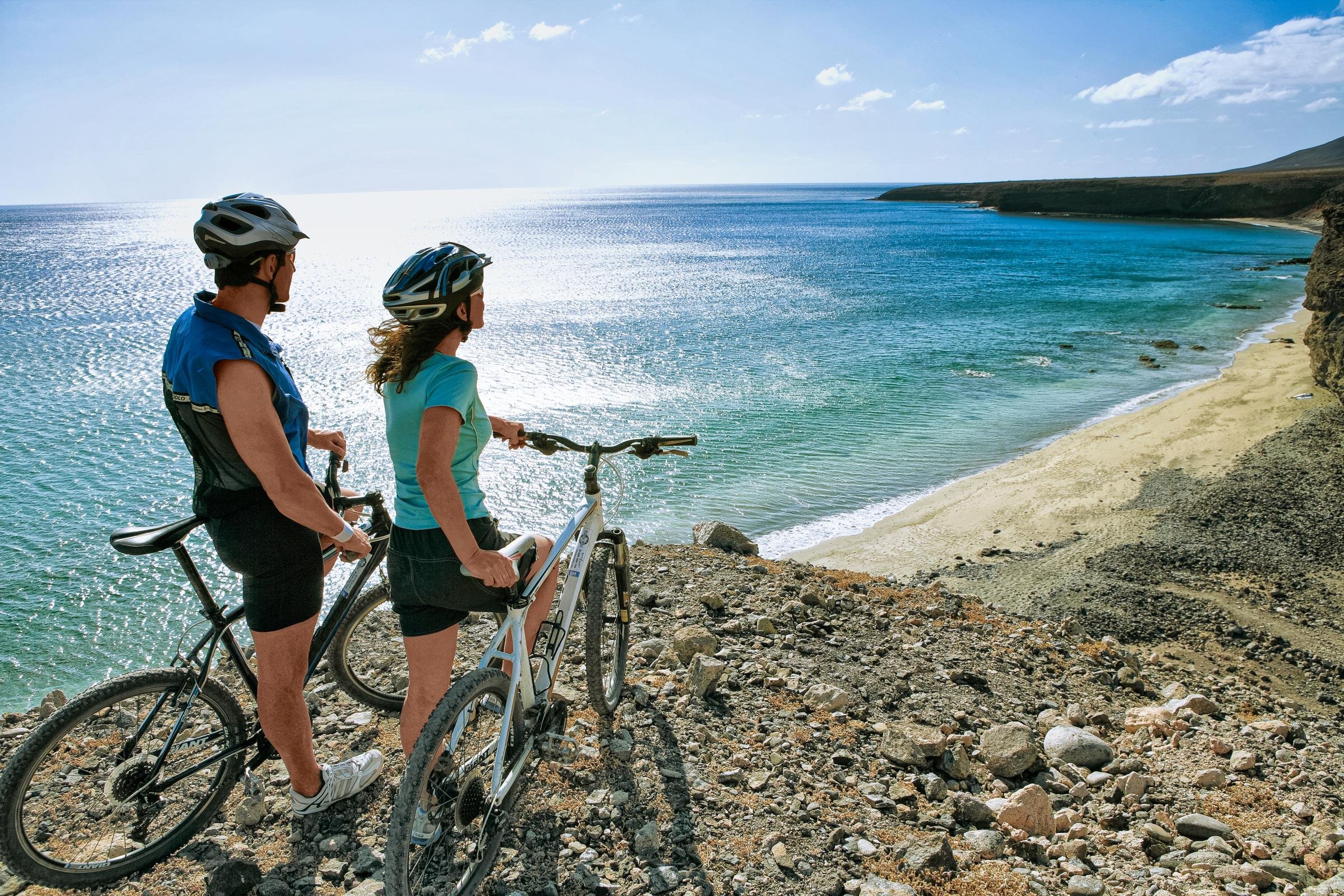 Zwei Frauen mit Fahrrad am Strand genießen die Natur bei einem Premium Cluburlaub