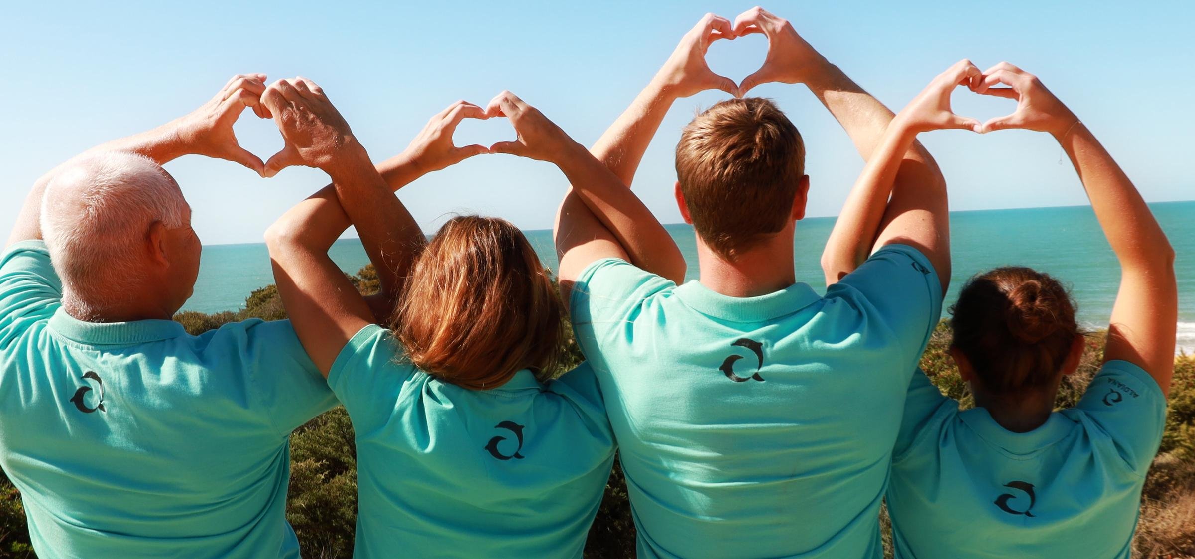 Vier Menschen am Strand beim Herzformen mit den Händen, genießen Premium Cluburlaub bei Aldiana