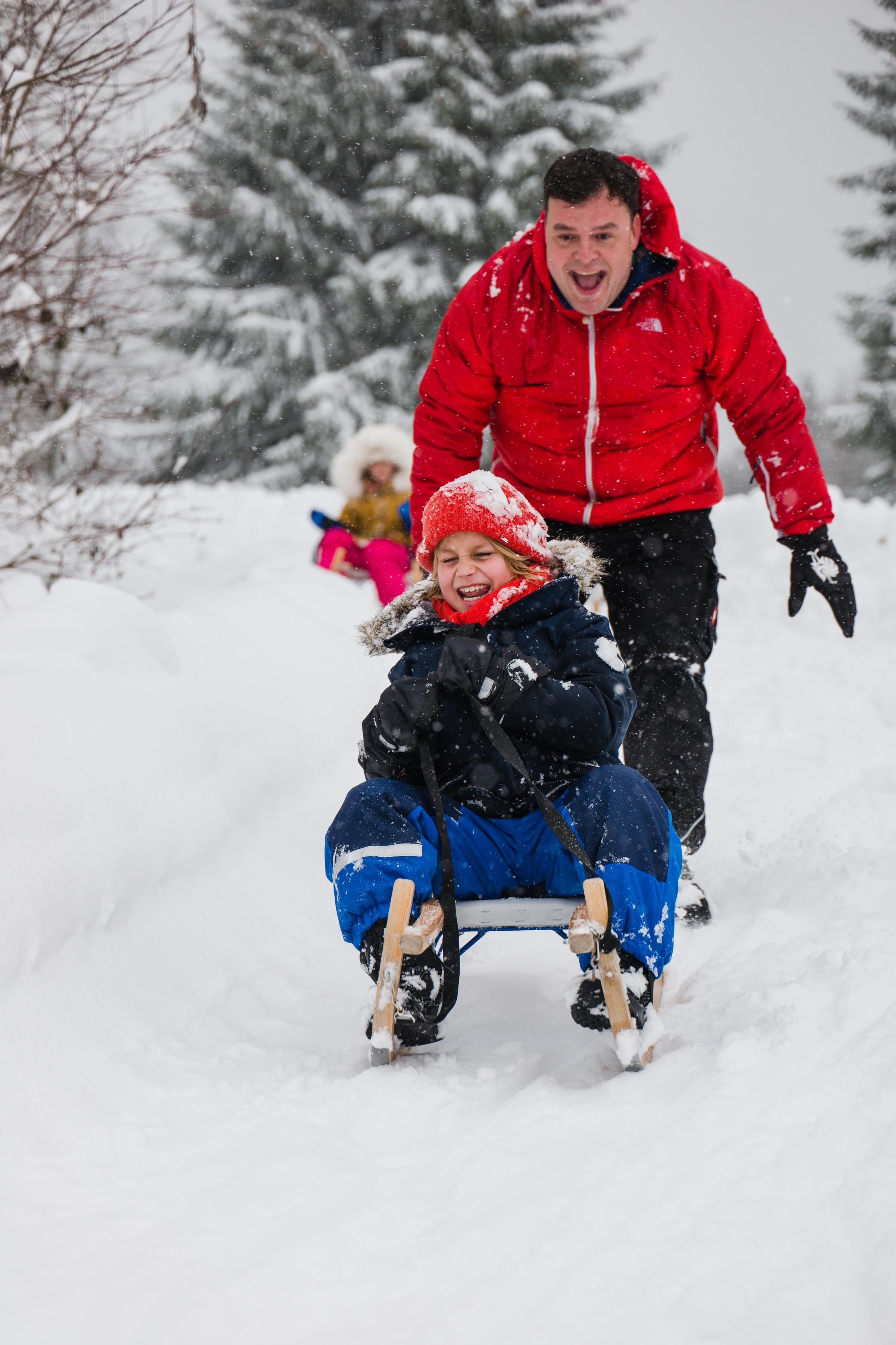 Familie beim Snowtubing im verschneiten Wald bei Aldiana, Premium Cluburlaub, winterlich