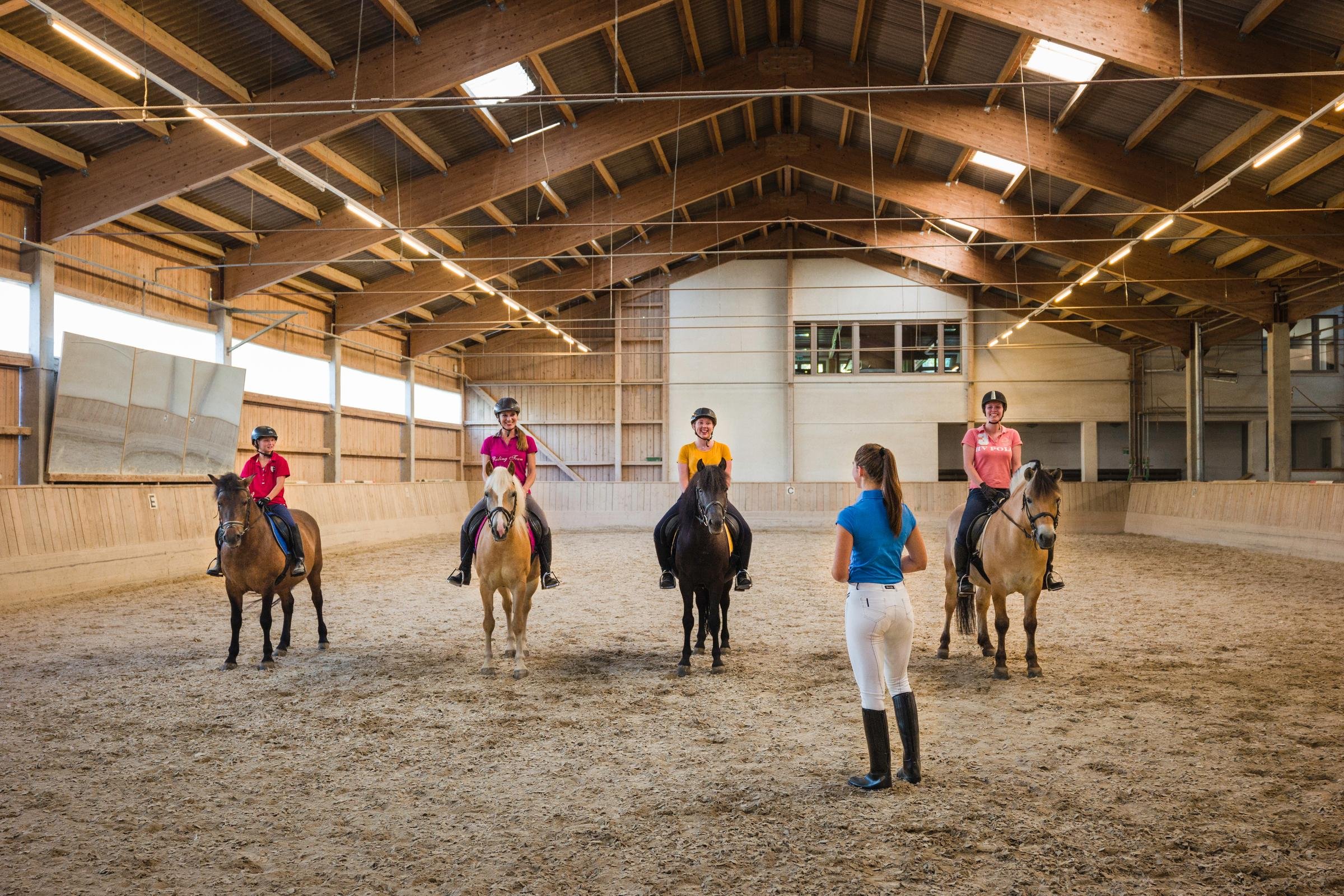 Reittraining im Indoor-Reitstall bei Aldiana mit Trainern und Kindern auf Pferden